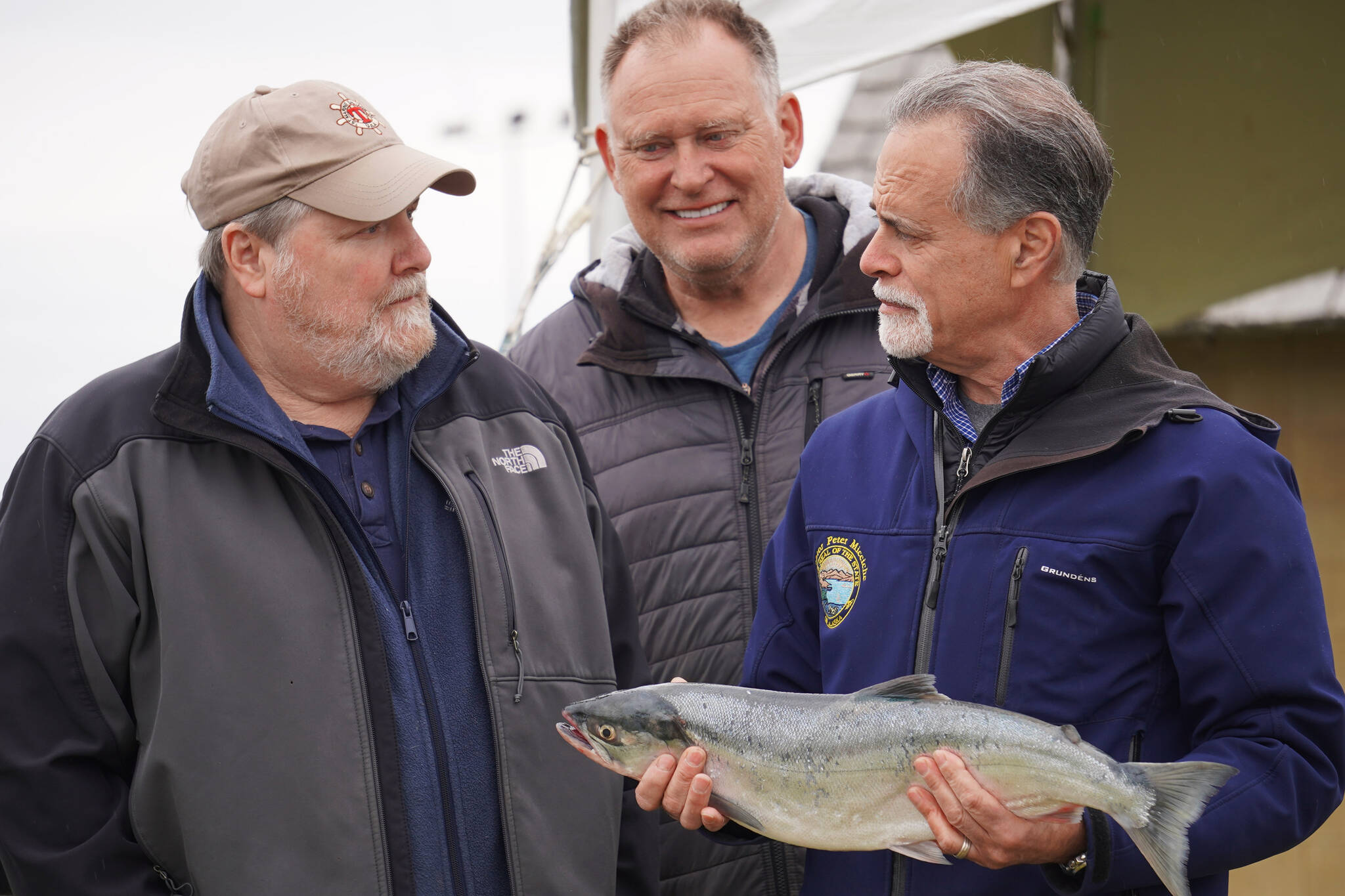 Auction winner Jim Butler, Angler Dave Chessik and auctioneer Peter Micciche stand together with the first sockeye of the season, sold for $58 a pound at Return of the Reds on Saturday, June 3, 2023, at the Kenai City Dock in Kenai, Alaska. (Jake Dye/Peninsula Clarion)