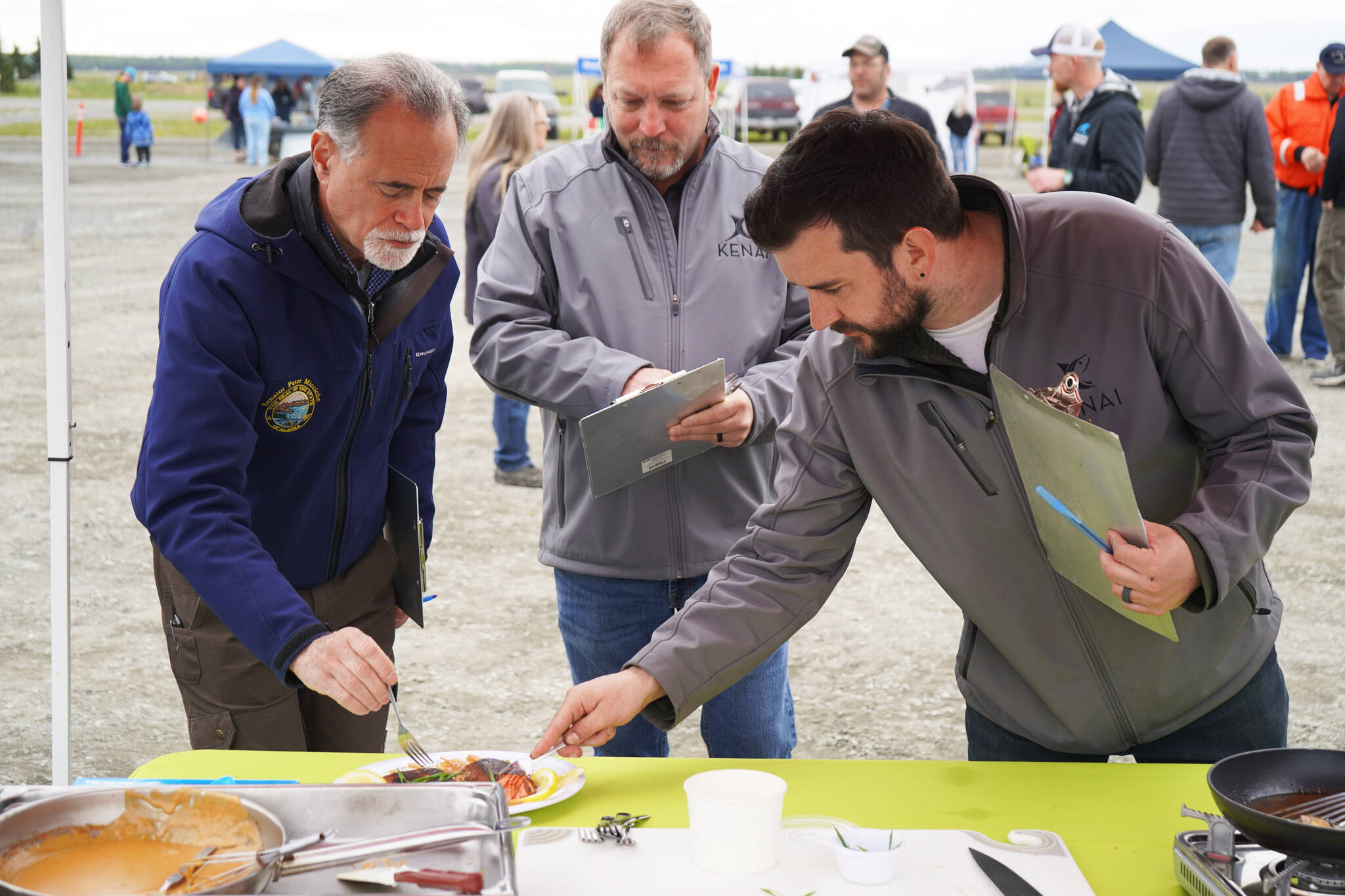 Judges Peter Micciche, Terry Eubank and Tyler Best sample a salmon dish prepared by chef Stephen Lamm of the Kenai Peninsula Food Bank at Return of the Reds on Saturday, June 3, 2023, at the Kenai City Dock in Kenai, Alaska. (Jake Dye/Peninsula Clarion)