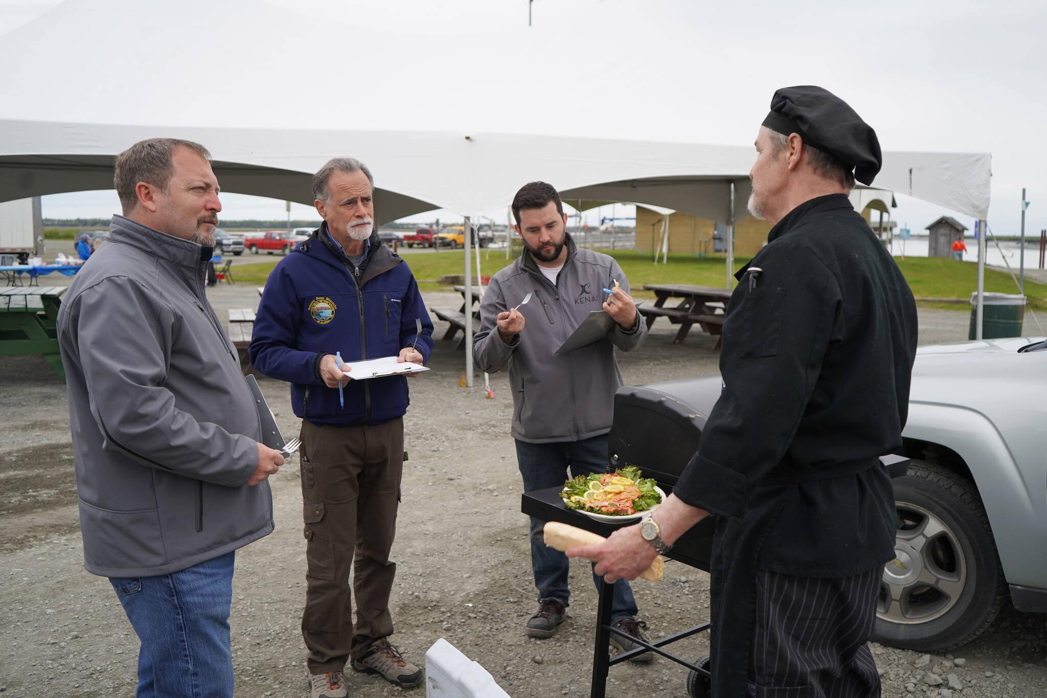 Judges Terry Eubank, Peter Micciche and Tyler Best sample a salmon dish prepared by chef Lastan Williams of The Catch at Return of the Reds on Saturday, June 3, 2023, at the Kenai City Dock in Kenai, Alaska. (Jake Dye/Peninsula Clarion)