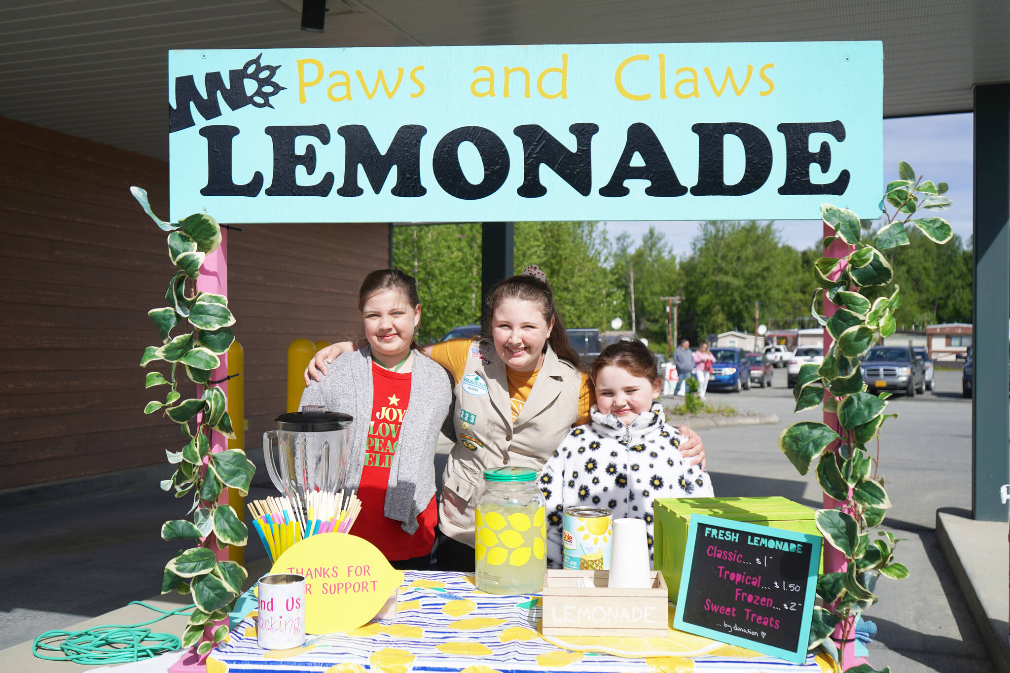 Hazel Teates, Lily Teates and Elladove Walls run Paws and Claws Lemonade by Northcountry Fair in Soldotna, Alaska, on Lemonade Day, Saturday, June 10, 2023. (Jake Dye/Peninsula Clarion)