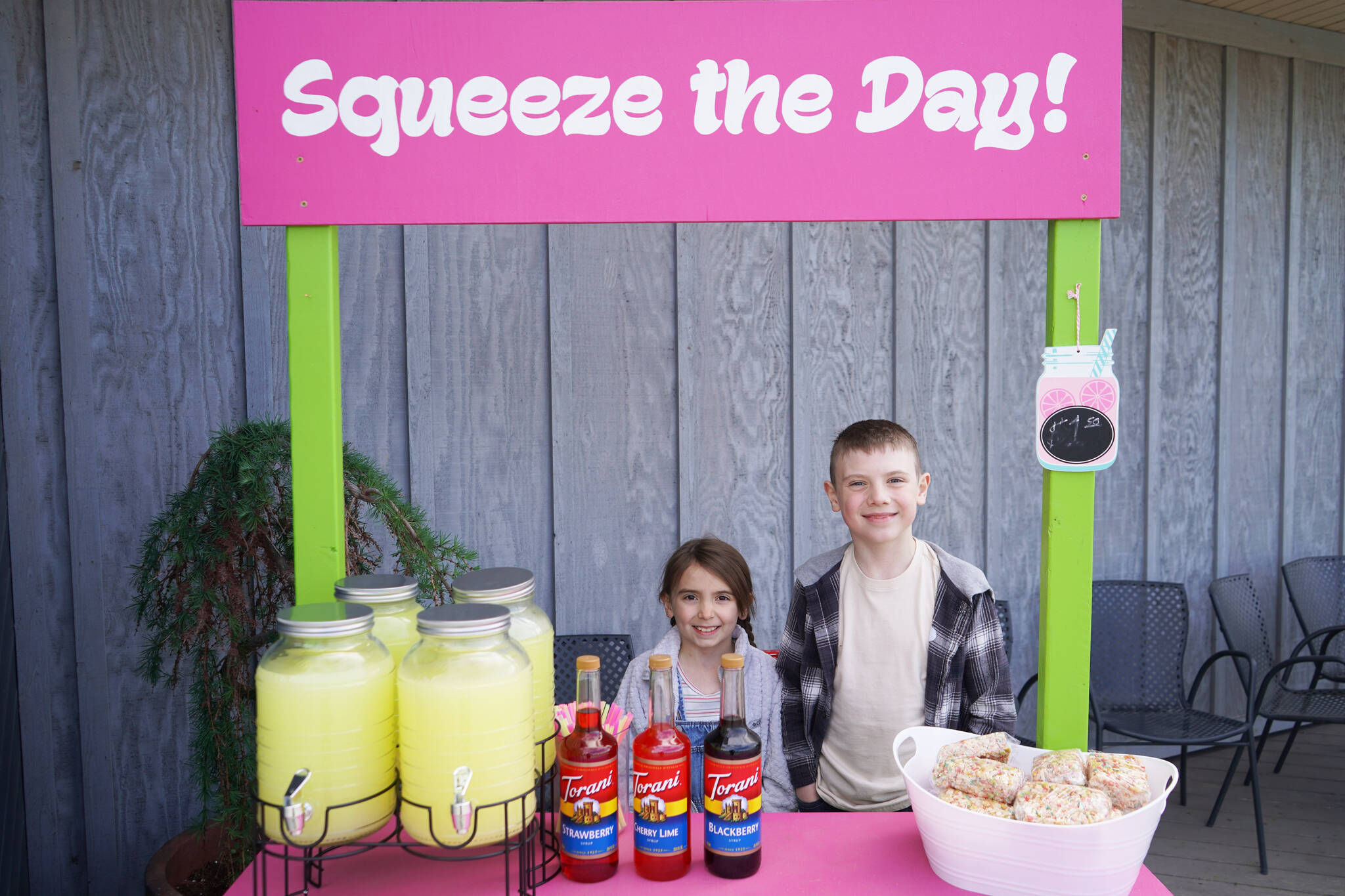 Ellie and Elias Ritter run Squeeze the Day in front of Odie’s Deli in Soldotna, Alaska, on Lemonade Day, Saturday, June 10, 2023. (Jake Dye/Peninsula Clarion)