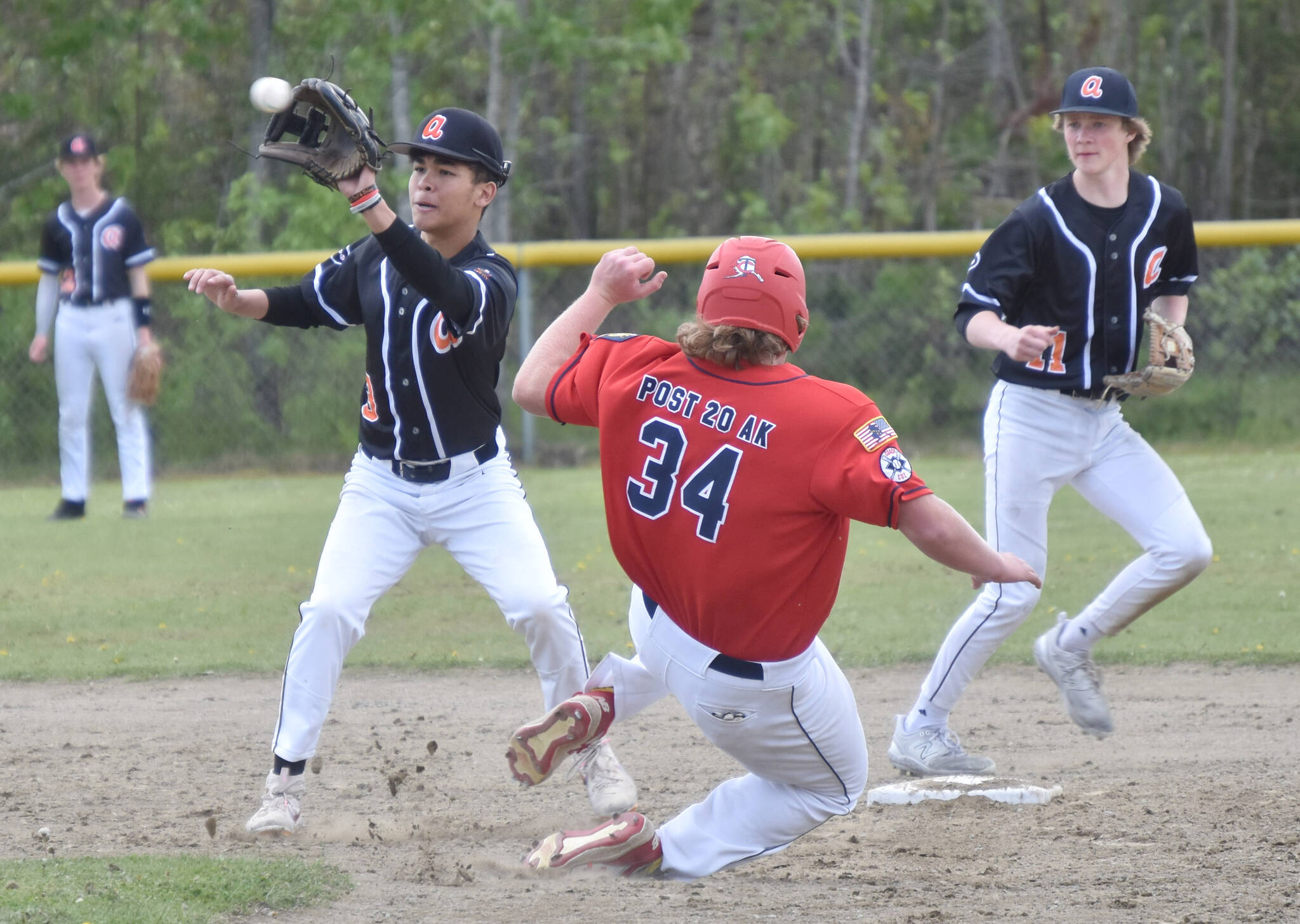 Charlie Chamberlain of the American Legion Twins beats the tag of West second baseman Orion Halliburton on Sunday, June 11, 2023, at the Soldotna Little League fields in Soldotna, Alaska. (Photo by Jeff Helminiak/Peninsula Clarion)