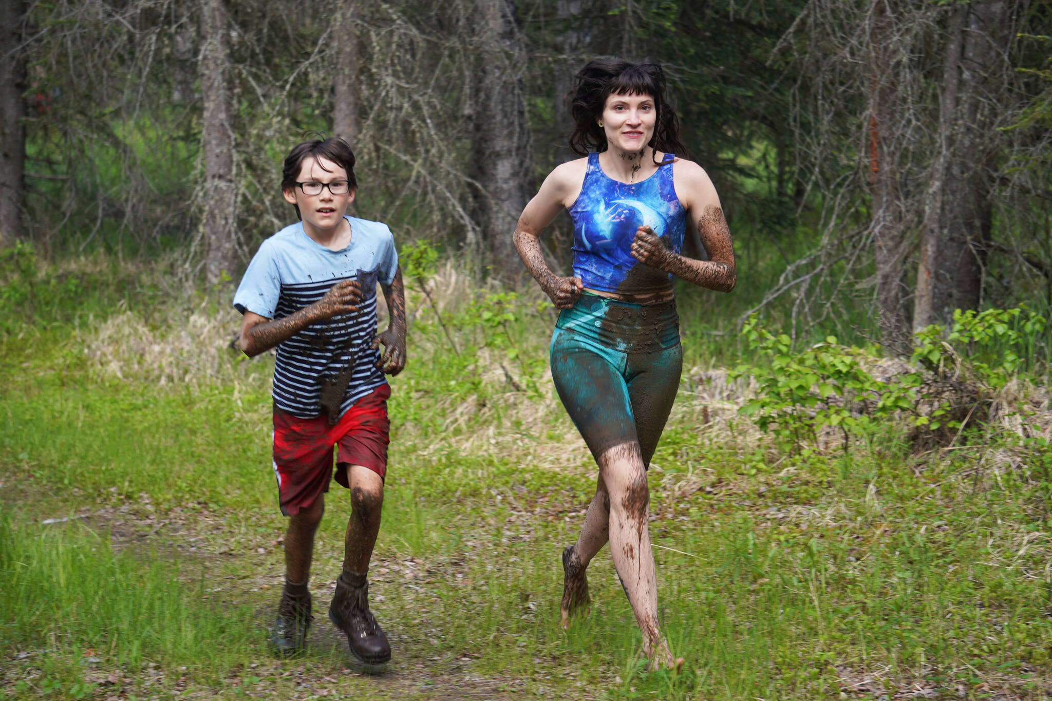 Muddy runners move down the Tsalteshi Trails’ Porcupine Loop in Soldotna, Alaska, as they participate in the KDLL Mud Run on Friday, June 16, 2023. (Jake Dye/Peninsula Clarion)