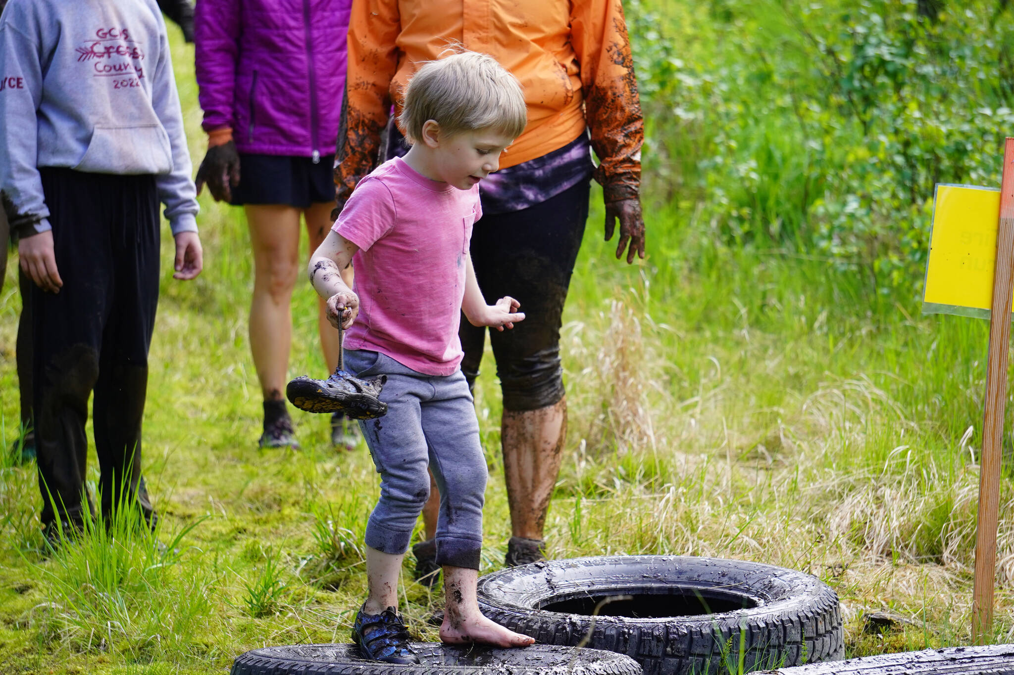 A young contestant balances carefully to avoid falling into the mud during the KDLL Mud Run at Tsalteshi Trails in Soldotna, Alaska, on Friday, June 16, 2023. (Jake Dye/Peninsula Clarion)