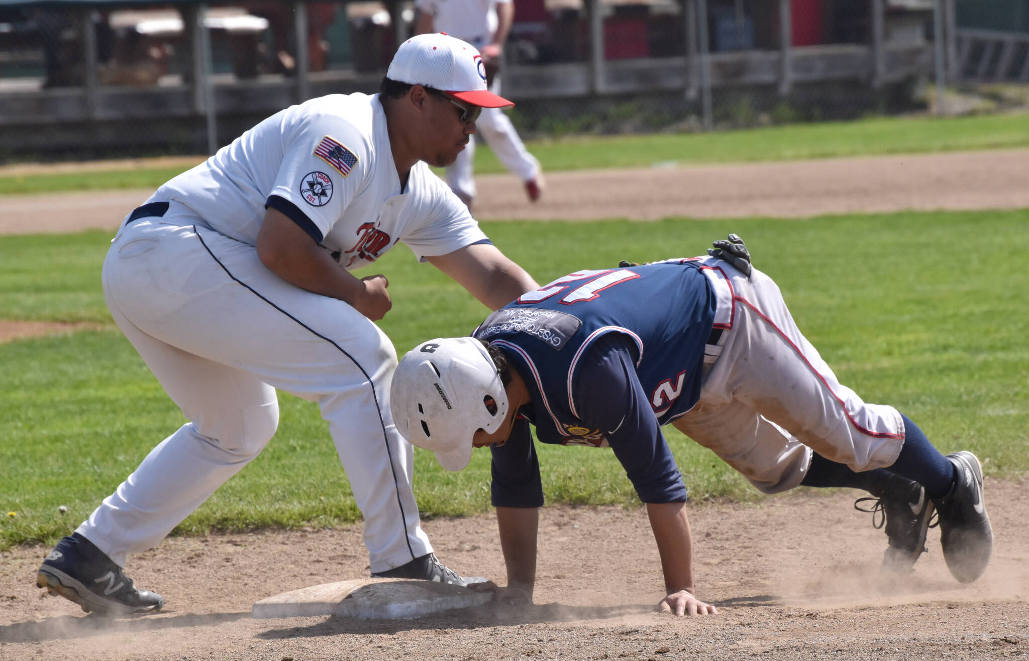 Wasilla Road Warriors’ Pedro Camacho slides under the tag of American Legion Twins first baseman Atticus Gibson on Sunday, June 18, 2023, at Coral Seymour Memorial Park in Kenai, Alaska. (Photo by Jeff Helminiak/Peninsula Clarion)