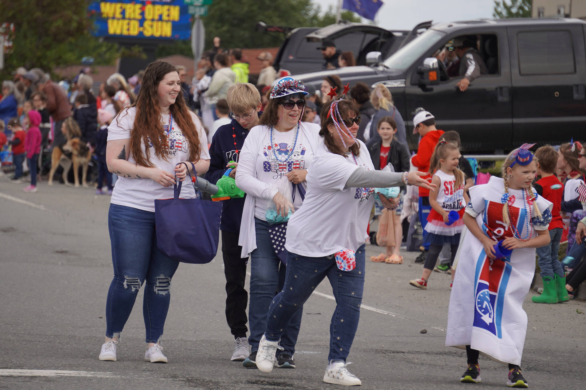 Denali Family Dentistry staff throw giveaways to children on the sidewalk as they turn onto the Kenai Spur Highway in Kenai, Alaska, during the Fourth of July Parade on Tuesday, July 4, 2023. (Jake Dye/Peninsula Clarion)