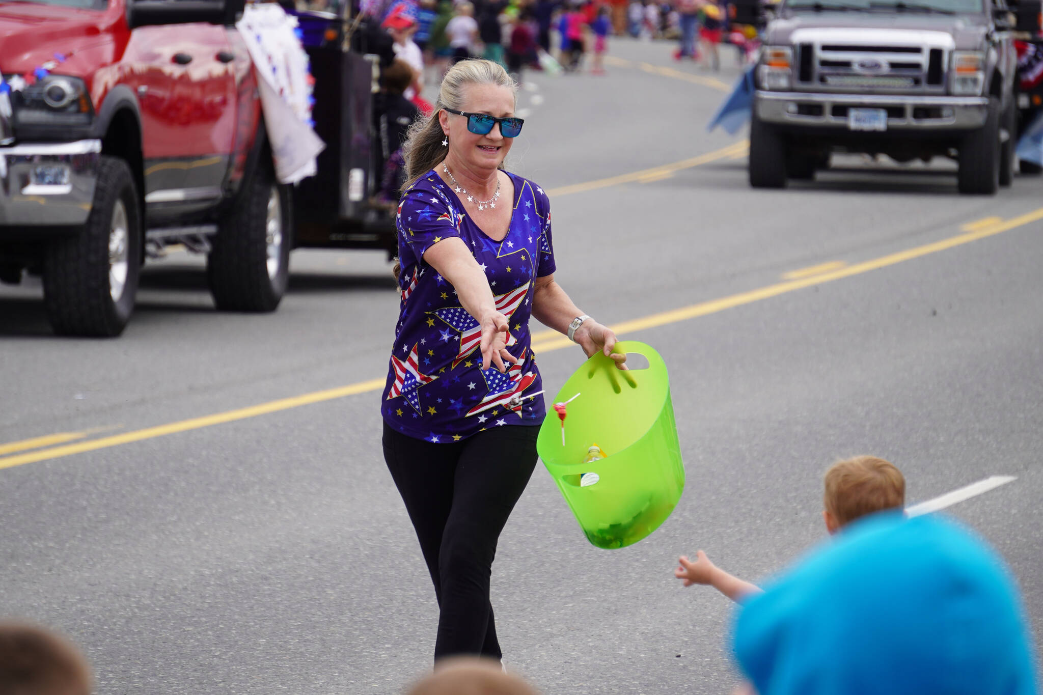 Children reach out for candy thrown as the Fourth of July Parade moves down the Kenai Spur Highway in Kenai, Alaska on Tuesday, July 4, 2023. (Jake Dye/Peninsula Clarion)