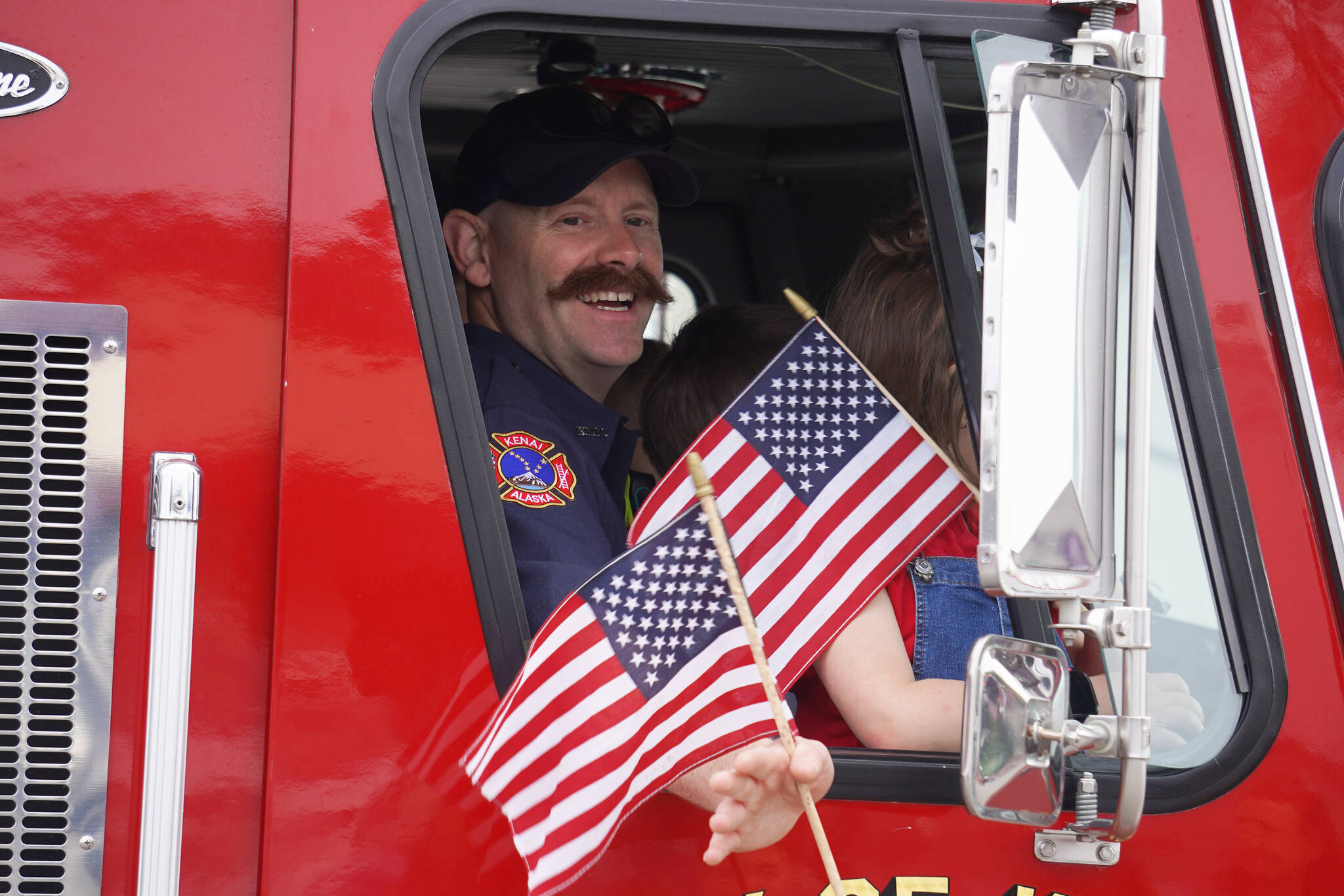 Mitch Miller, of Kenai Fire Department, smiles and waves as the Fourth of July Parade moves down the South Willow Street in Kenai, Alaska on Tuesday, July 4, 2023. (Jake Dye/Peninsula Clarion)