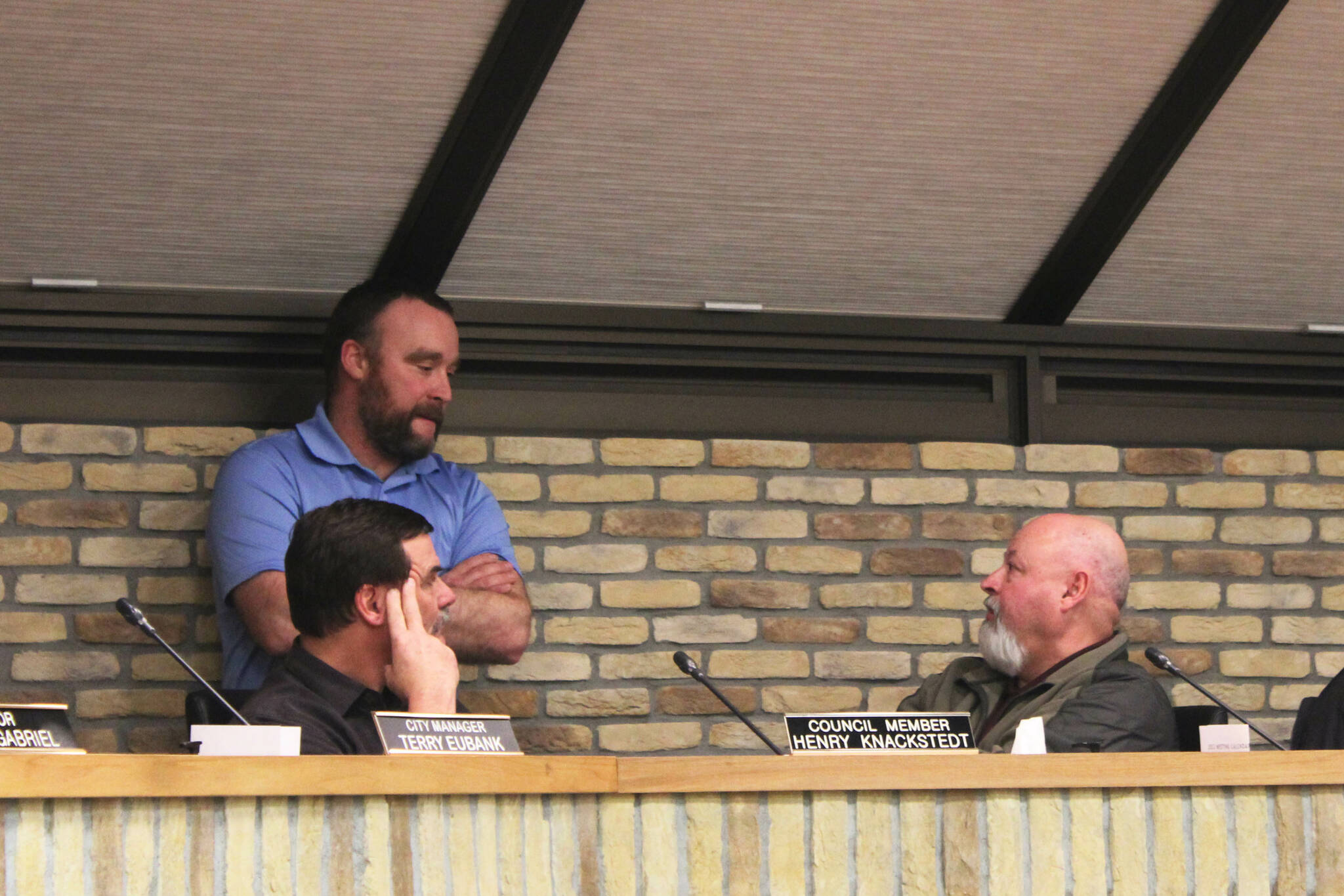 Kenai City Council members Henry Knackstedt (left) and Alex Douthit (standing) speak with Kenai Vice Mayor James Baisden (right) during a council meeting at-ease on Wednesday, Feb. 1, 2023 in Kenai, Alaska. (Ashlyn O’Hara/Peninsula Clarion)