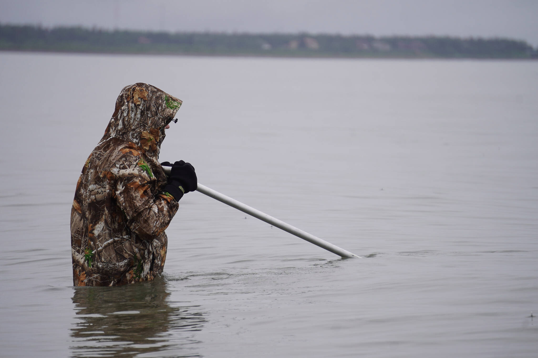 Jacob Cook, of Wasilla, stands in the mouth of the Kenai River with a dipnet extended on Monday, July 10, 2023, at the Kenai Beach in Kenai, Alaska. (Jake Dye/Peninsula Clarion)