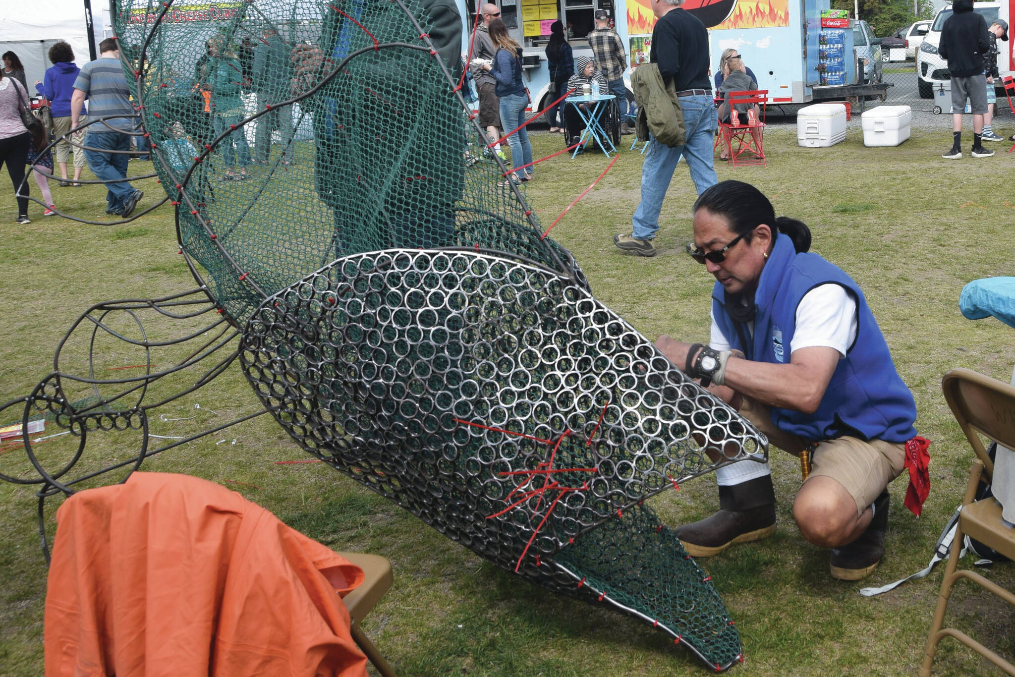 Cam Choy, associate professor of art at Kenai Peninsula College, works on a salmon sculpture in collaboration with the Kenai Watershed Forum during the Kenai River Festival at Soldotna Creek Park in Soldotna, Alaska, on June 8, 2019. (Photo by Brian Mazurek/Peninsula Clarion)