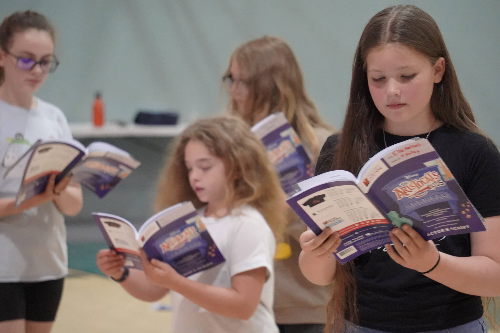 Ella Mallard, right, checks her lines during a rehersal of “The Aristocats Kids” during a Triumvirate Theatre drama camp on Wednesday, July 19, 2023 at the Boys and Girls Club of the Kenai Peninsula Main Office in Kenai, Alaska. (Jake Dye/Peninsula Clarion)