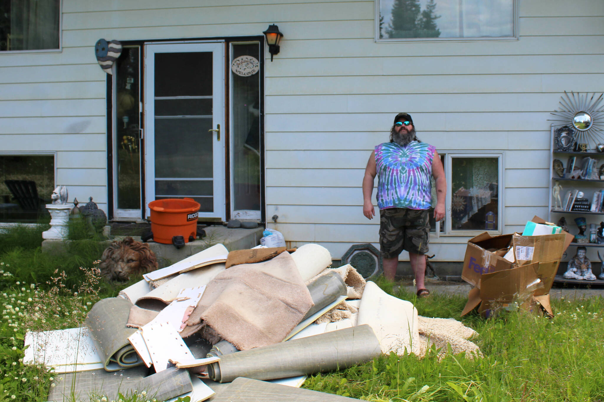 Marcus Ashkenasy stands near a pile of water-damaged carpet pulled from the bottom level of his house on Monday, July 24, 2023 near Kenai, Alaska. (Ashlyn O’Hara/Peninsula Clarion)