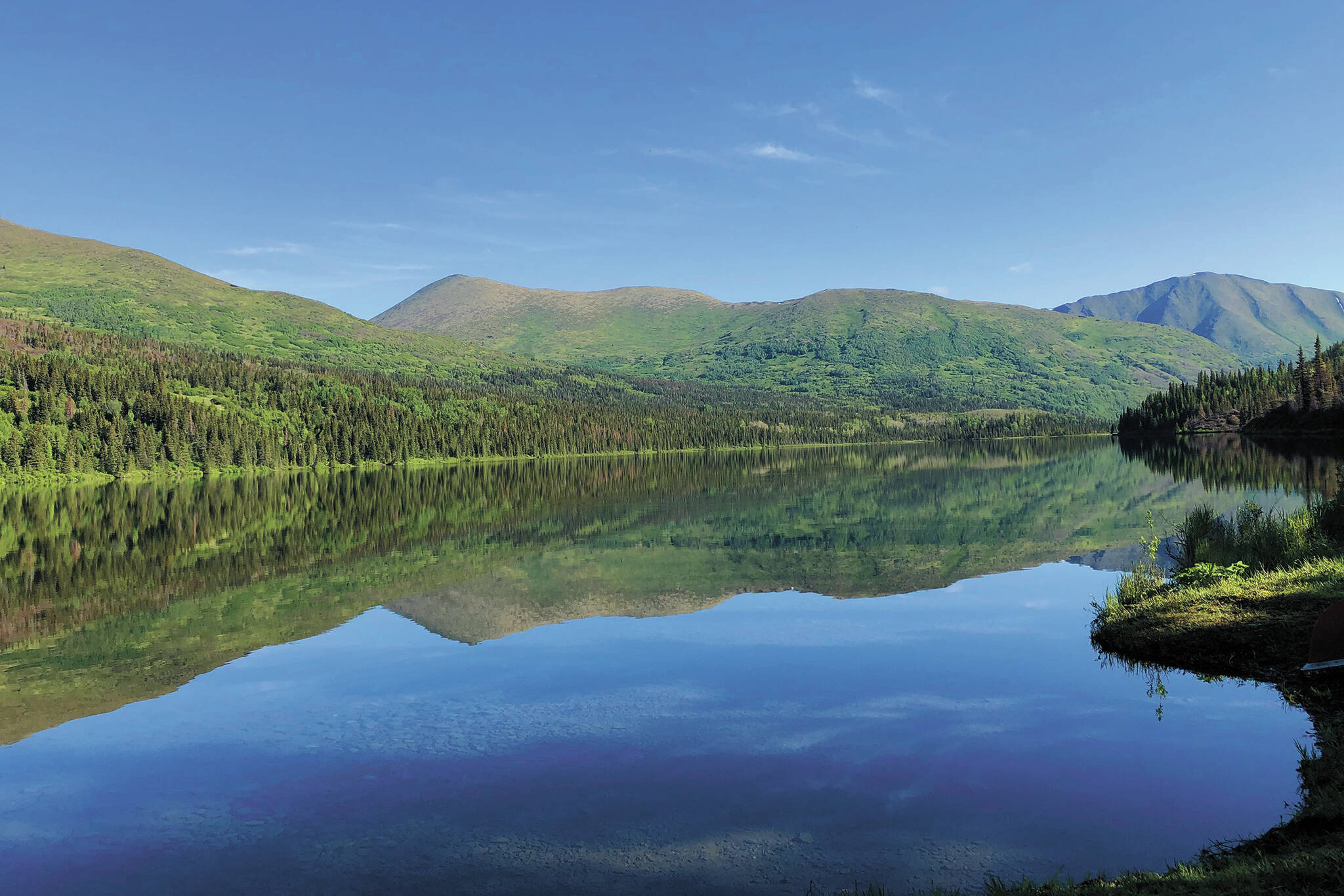 Juneau Lake shows off the reflection of its surrounding mountains on June 27, 2020 about 9 miles down Resurrection Pass in Cooper Landing, Alaska. (Photo by Megan Pacer/Homer News)