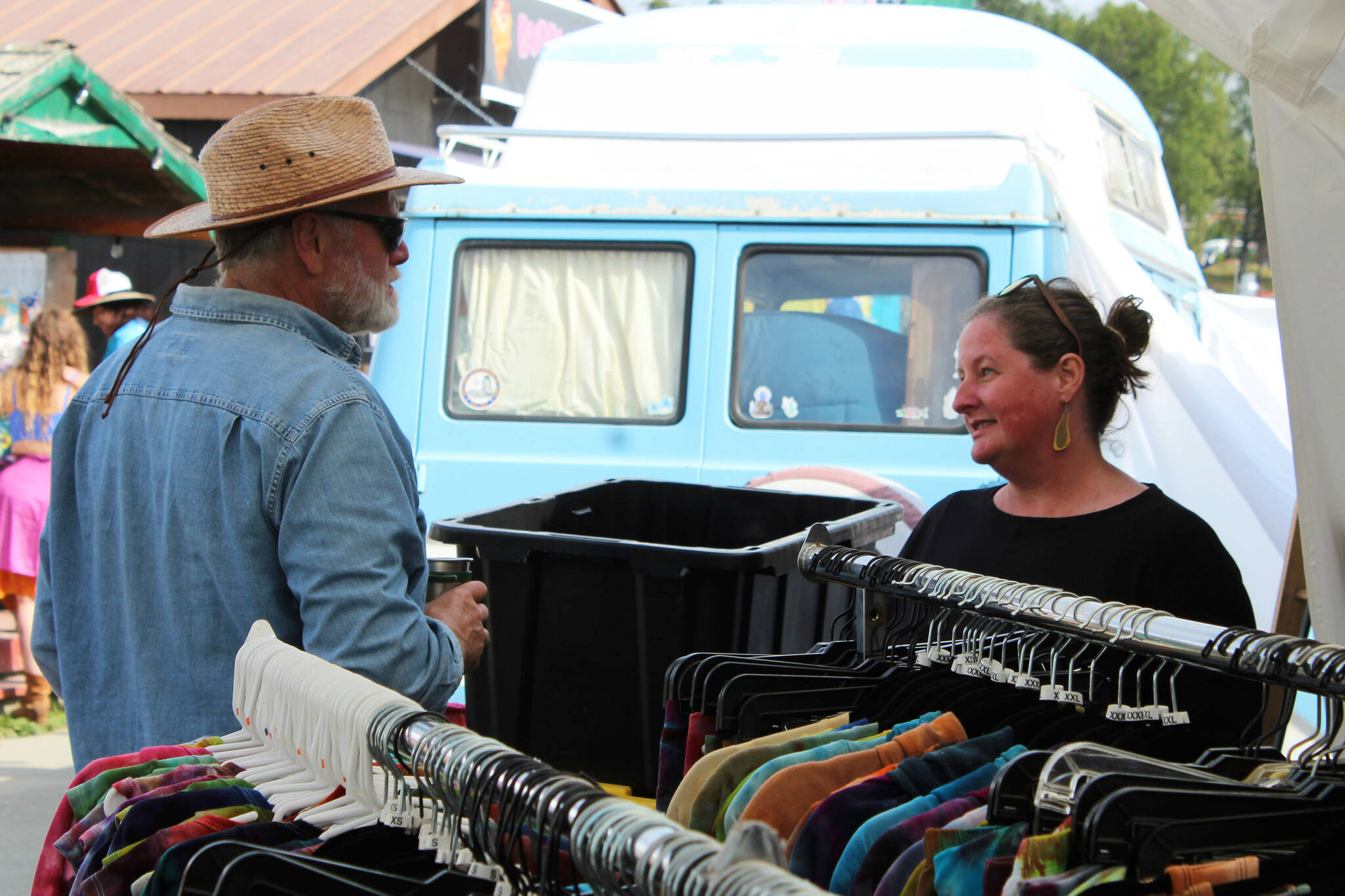 Drunken Forest Tie Dye owner Jen Luton (right) assists a customer at her vendor booth at Salmonfest on Friday, Aug. 4, 2023 in Ninilchik, Alaska. (Ashlyn O'Hara/Peninsula Clarion)