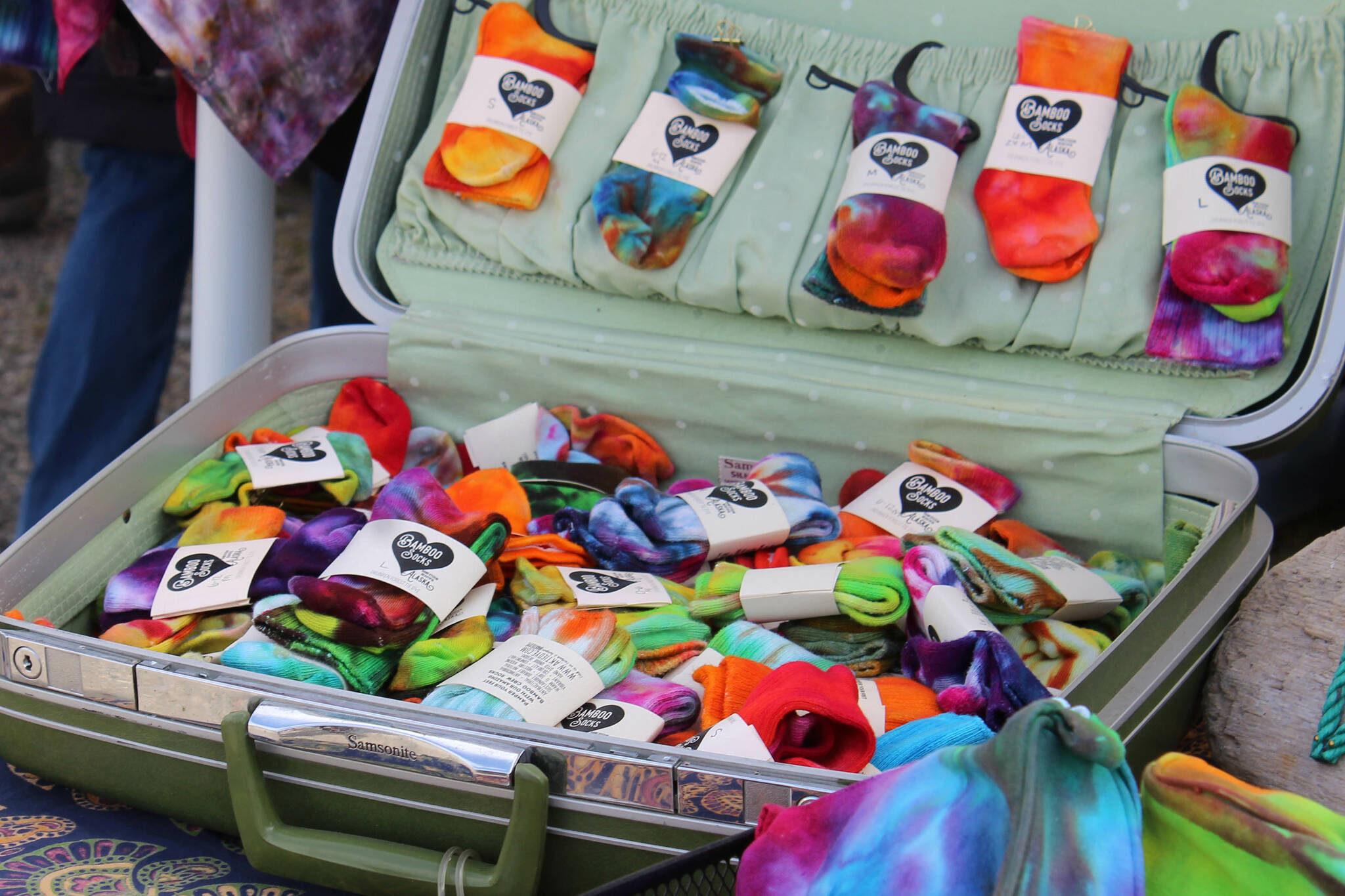 Tie dye socks fill a suitcase at Jen Luton's Drunken Forest Tie Dye booth at Salmonfest on Friday, Aug. 4, 2023 in Ninilchik, Alaska. (Ashlyn O'Hara/Peninsula Clarion)