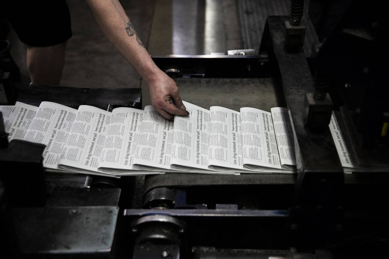 Mike Tullar grabs a Herald to check over as the first papers roll off the press on Wednesday, March 30, 2022 in Everett, Washington. (Olivia Vanni / The Herald)