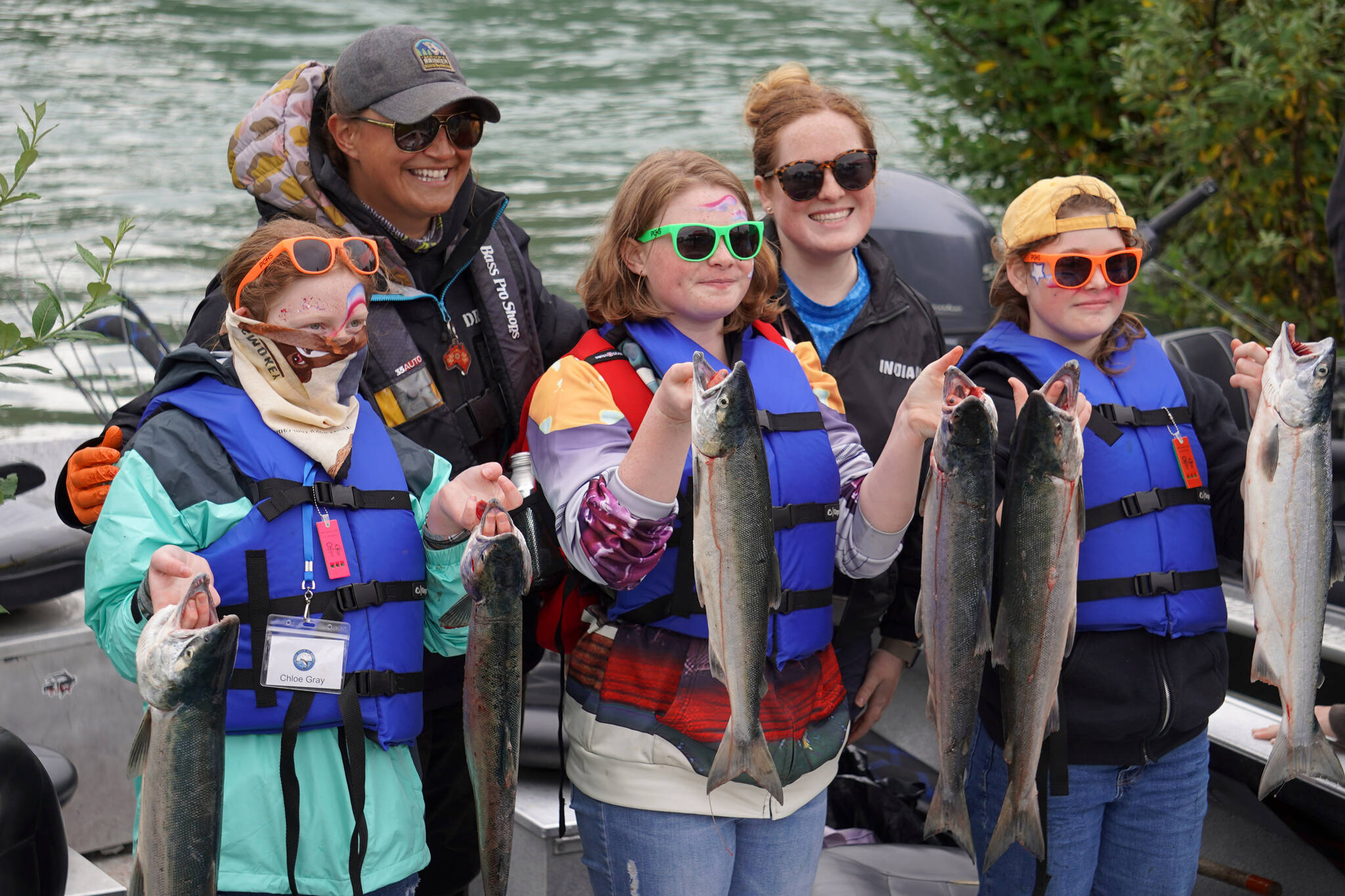 Chloe Gray and other occupants of a guide boat hold up six salmon they caught during the Kenai River Junior Classic in Soldotna, Alaska, on Wednesday, Aug. 9, 2023. (Jake Dye/Peninsula Clarion)