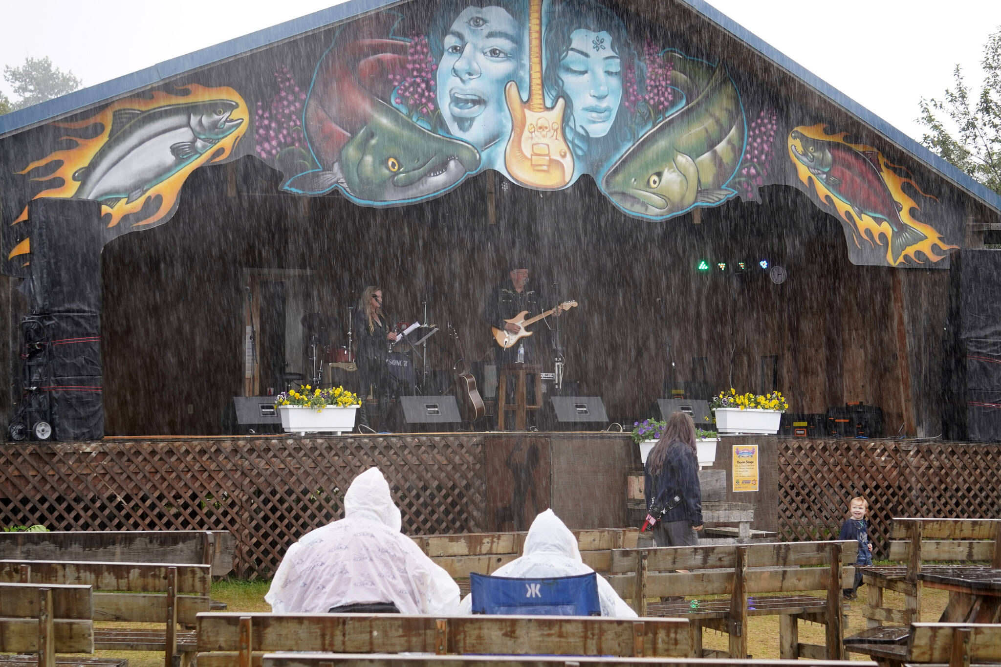 Karin Caldwell and Mark Hutton perform under rainfall on the Ocean Stage at the Kenai Peninsula Fair in Ninilchik, Alaska, on Friday, Aug. 11, 2023. (Jake Dye/Peninsula Clarion)