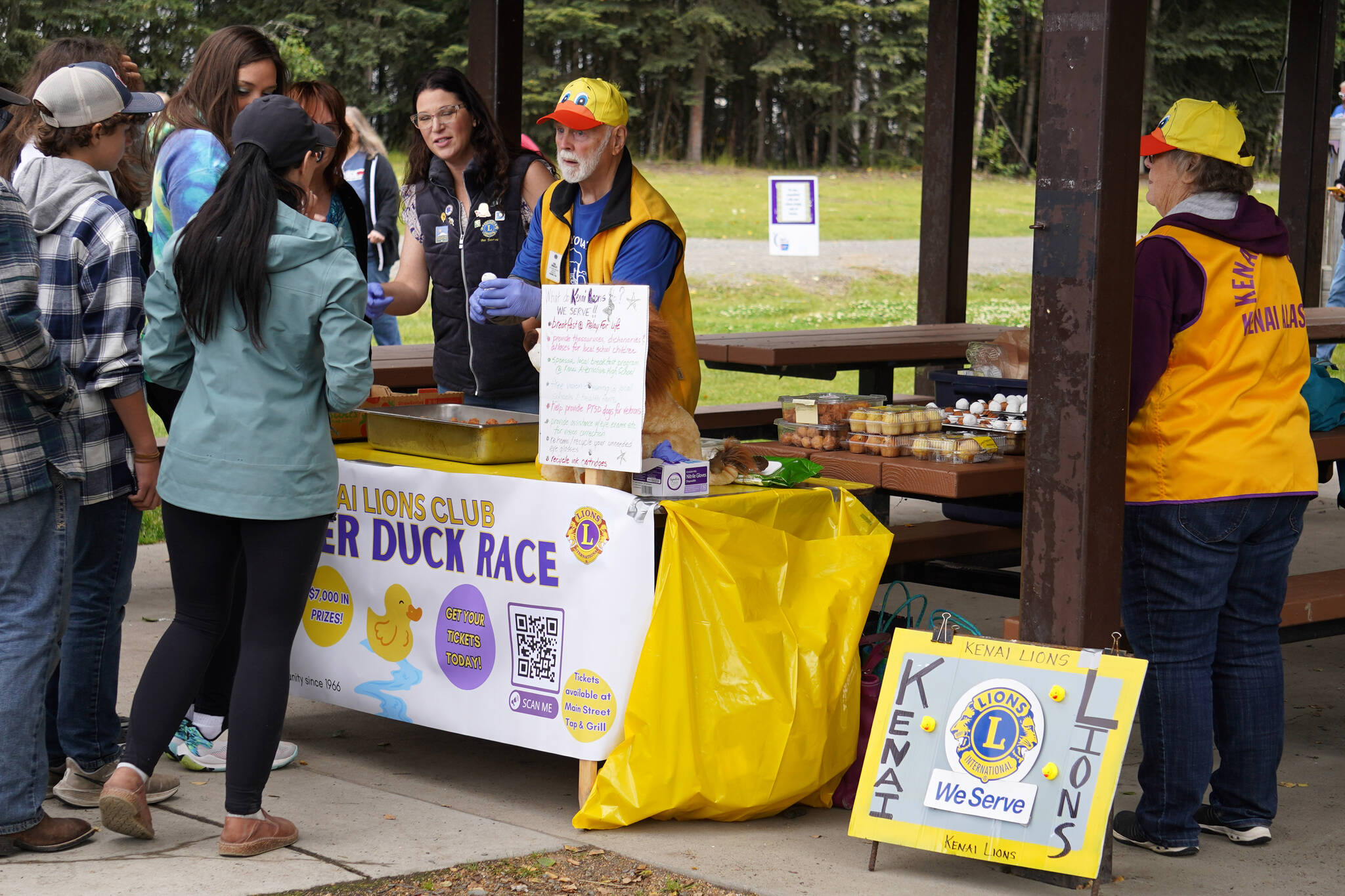 Members of the Kenai Lions Club pass out donuts to participants of the Brewery to Bathroom .5K at Soldotna Creek Park in Soldotna, Alaska, on Sunday, Aug. 13, 2023. (Jake Dye/Peninsula Clarion)