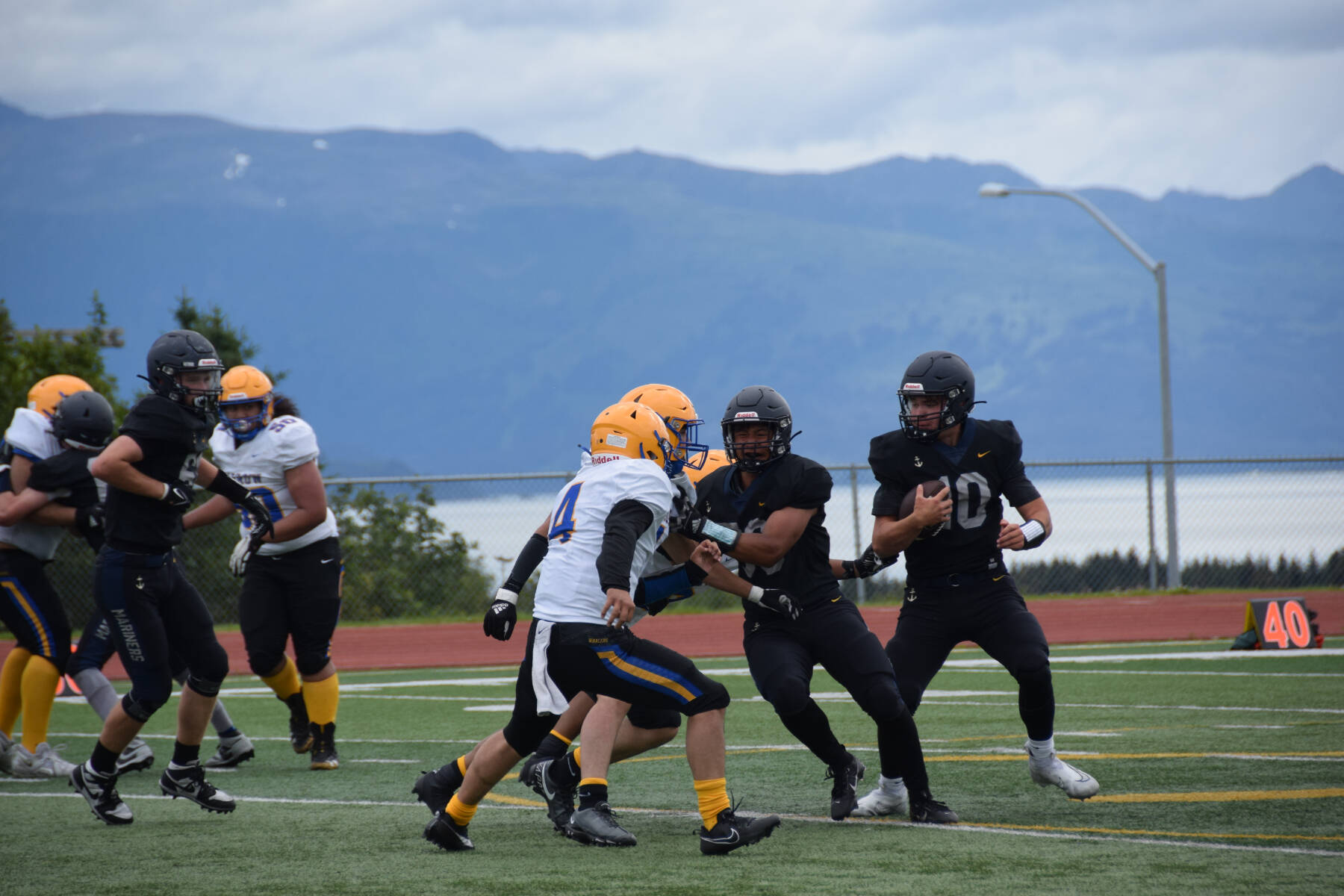 Homer’s Preston Stanislaw defends the ball from Barrow in the third quarter before passing it to Jonah Martin, who scores a touchdown and brings the Mariners’ score up to 36 points during the home opener varsity game on Saturday, Aug. 12, 2023 in Homer, Alaska. (Delcenia Cosman/Homer News)
