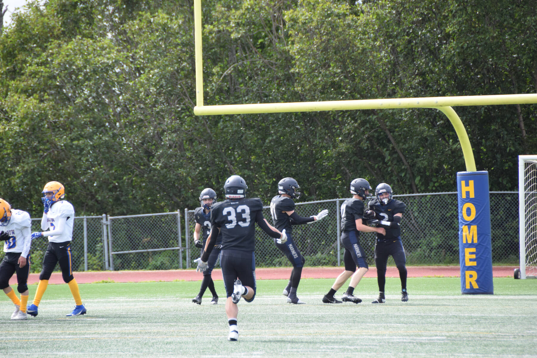 Chris Martishev’s teammates congratulate him after he caught a 58-yard pass from quarterback Preston Stanislaw, scoring a touchdown and bringing the Mariners’ score up to eight points in the first quarter of the home opener varsity game on Saturday, Aug. 12, 2023 in Homer, Alaska. (Delcenia Cosman/Homer News)