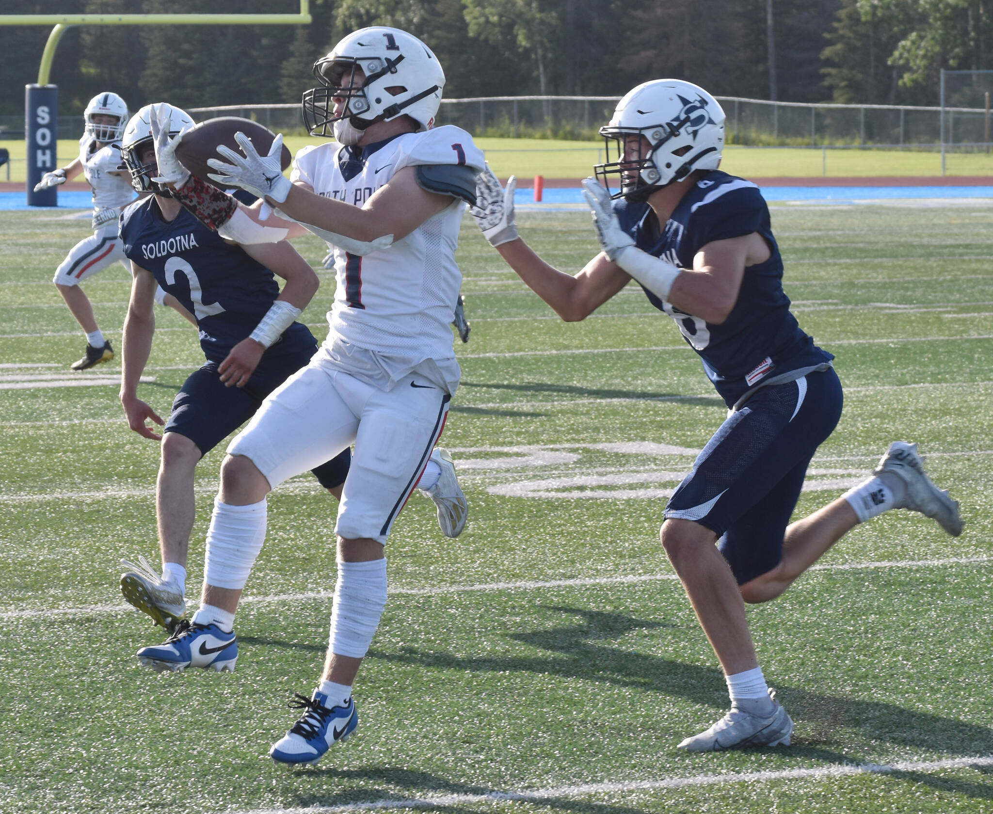 North Pole’s Izak D’Hondt catches a pass in front of Soldotna defenders Leigh Tacey and Trevor Michael on Friday, Aug. 18, 2023, at Justin Maile Field at Soldotna High School in Soldotna, Alaska. (Photo by Jeff Helminiak/Peninsula Clarion)