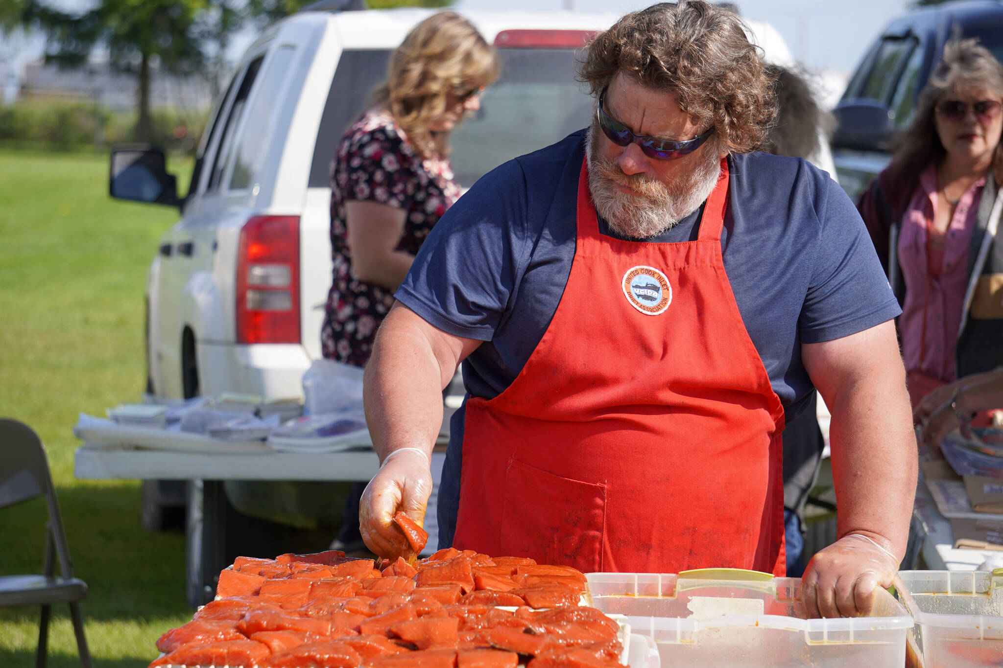 Members of the United Cook Inlet Drift Association prepare salmon for barbecuing during Industry Appreciation Day festivities at the Kenai softball greenstrip in Kenai, Alaska, on Saturday, Aug. 19, 2023. (Jake Dye/Peninsula Clarion)