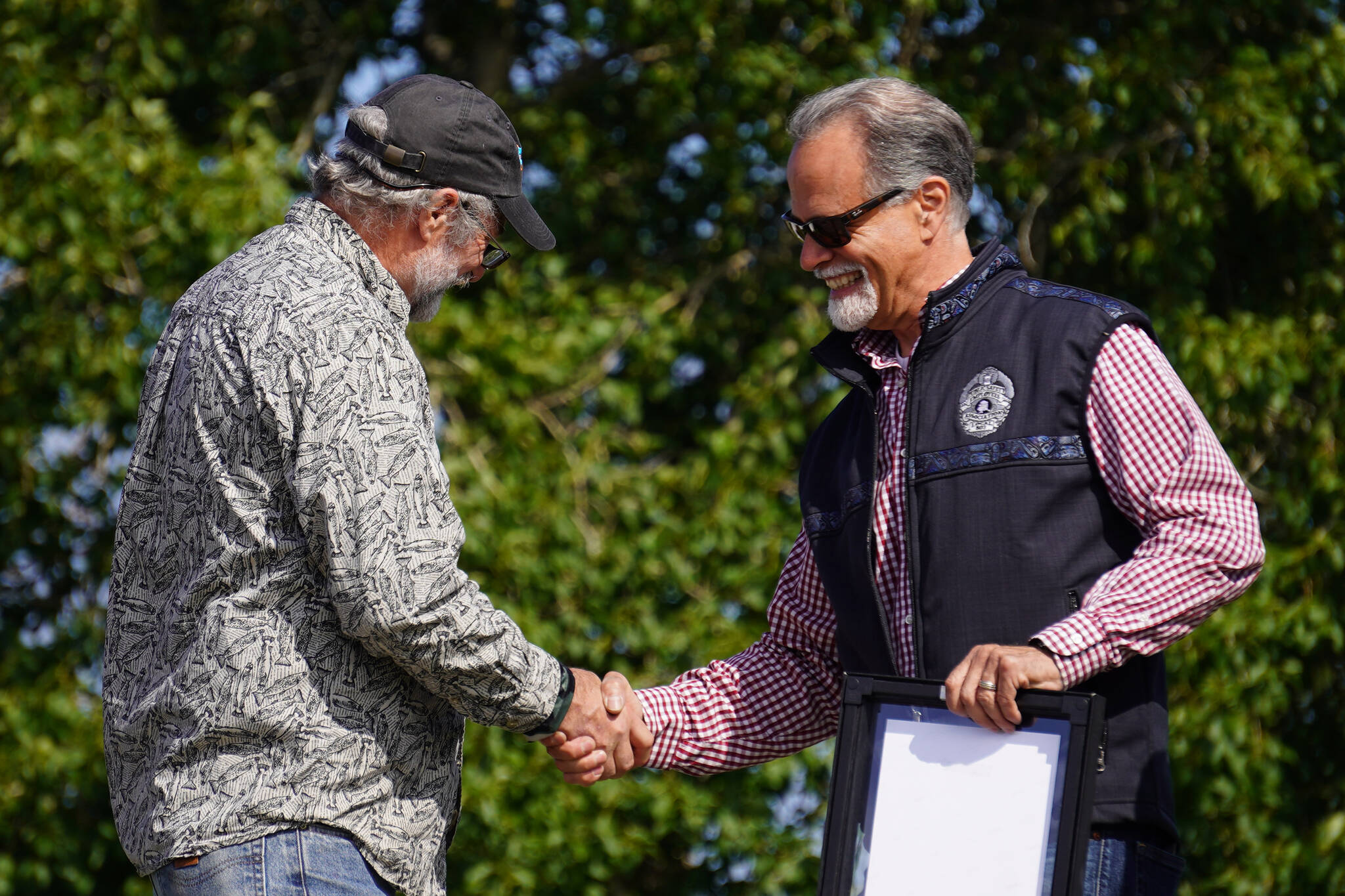 Dyer VanDevere receives the Outstanding Individual Commercial Fishing Contribution Award from Kenai Peninsula Borough Mayor Peter Micciche during Industry Appreciation Day festivities at the Kenai softball greenstrip on Saturday, Aug. 19, 2023. (Jake Dye/Peninsula Clarion)