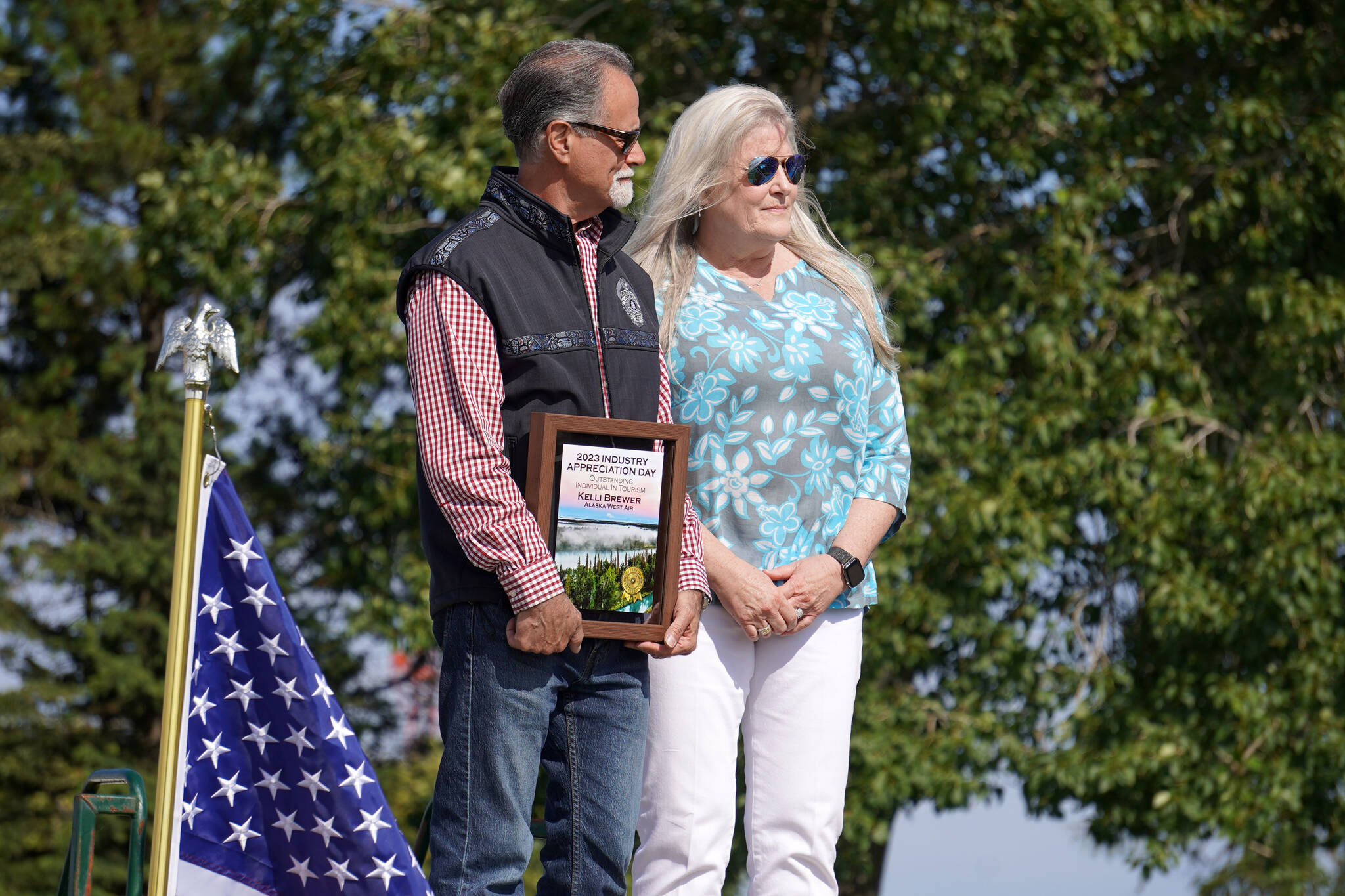 Kelli Brewer, right, receives the Outstanding Individual in Tourism Award from Kenai Peninsula Borough Mayor Peter Micciche during Industry Appreciation Day festivities at the Kenai softball greenstrip on Saturday, Aug. 19, 2023. (Jake Dye/Peninsula Clarion)