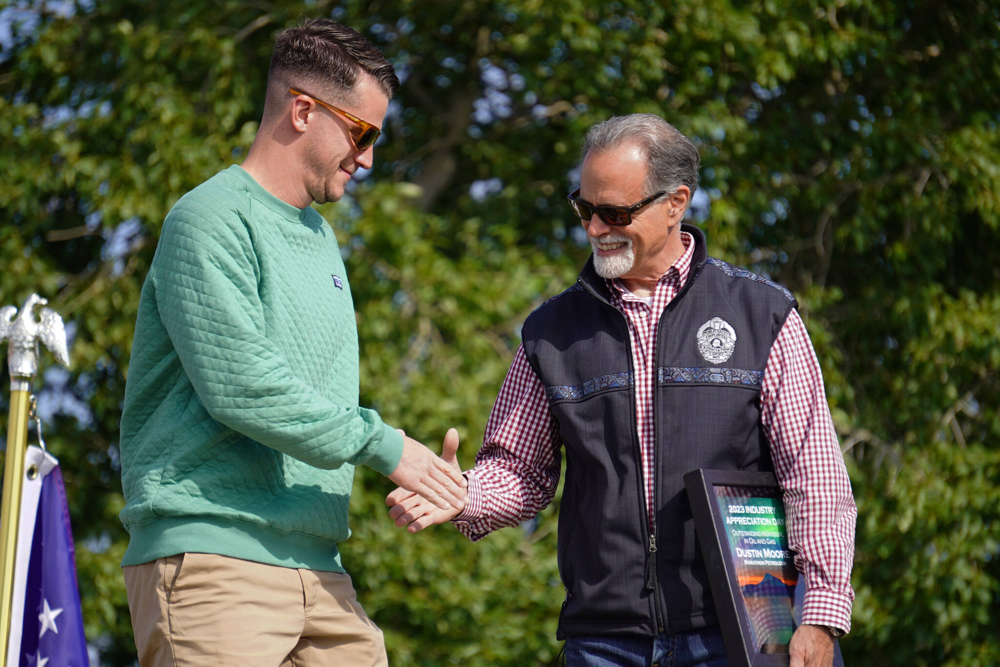 Dustin Moore receives the Outstanding Individual in Oil and Gas Award from Kenai Peninsula Borough Mayor Peter Micciche during Industry Appreciation Day festivities at the Kenai softball greenstrip on Saturday, Aug. 19, 2023. (Jake Dye/Peninsula Clarion)