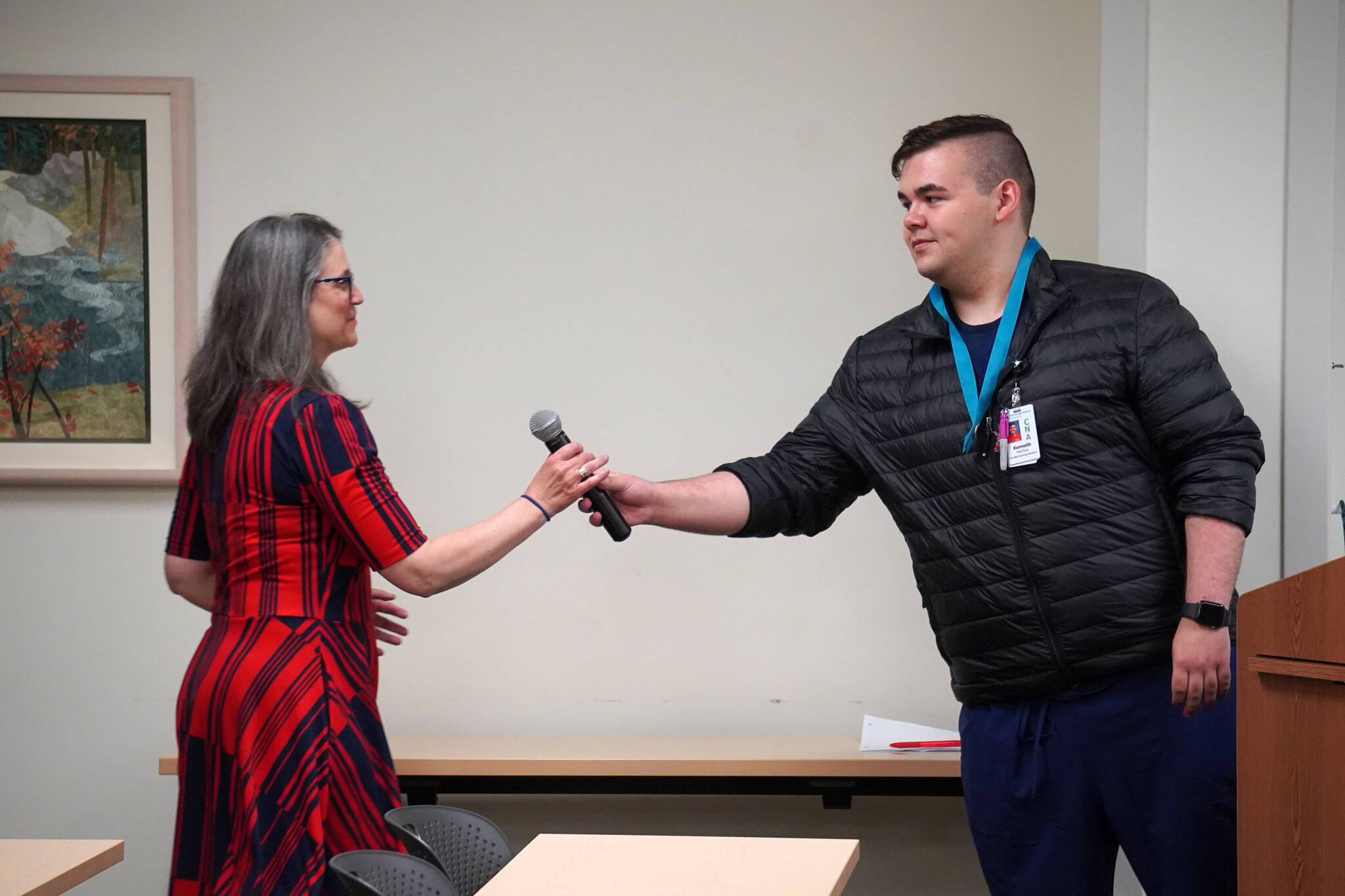 Ana Monyahan takes the microphone from Kenneth Coghill II after his speech at a graduation ceremony at Central Peninsula Hospital in Soldotna, Alaska, on Friday, Aug. 25, 2023. (Jake Dye/Peninsula Clarion)
