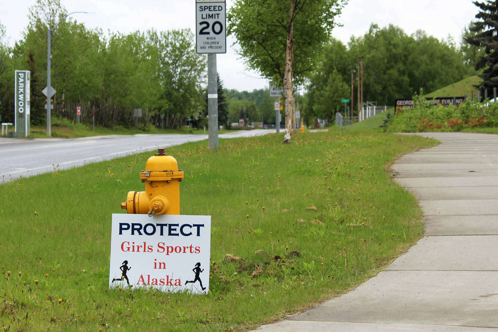 A sign opposing the participation of trans girls in girls sports is propped against a fire hydrant outside of the George A. Navarre Admin Building on Thursday, June 8, 2023, in Soldotna, Alaska. The Alaska Board of Education met in the building to discuss a resolution that would ban trans girls from girls high school sports. (Ashlyn O’Hara/Peninsula Clarion)