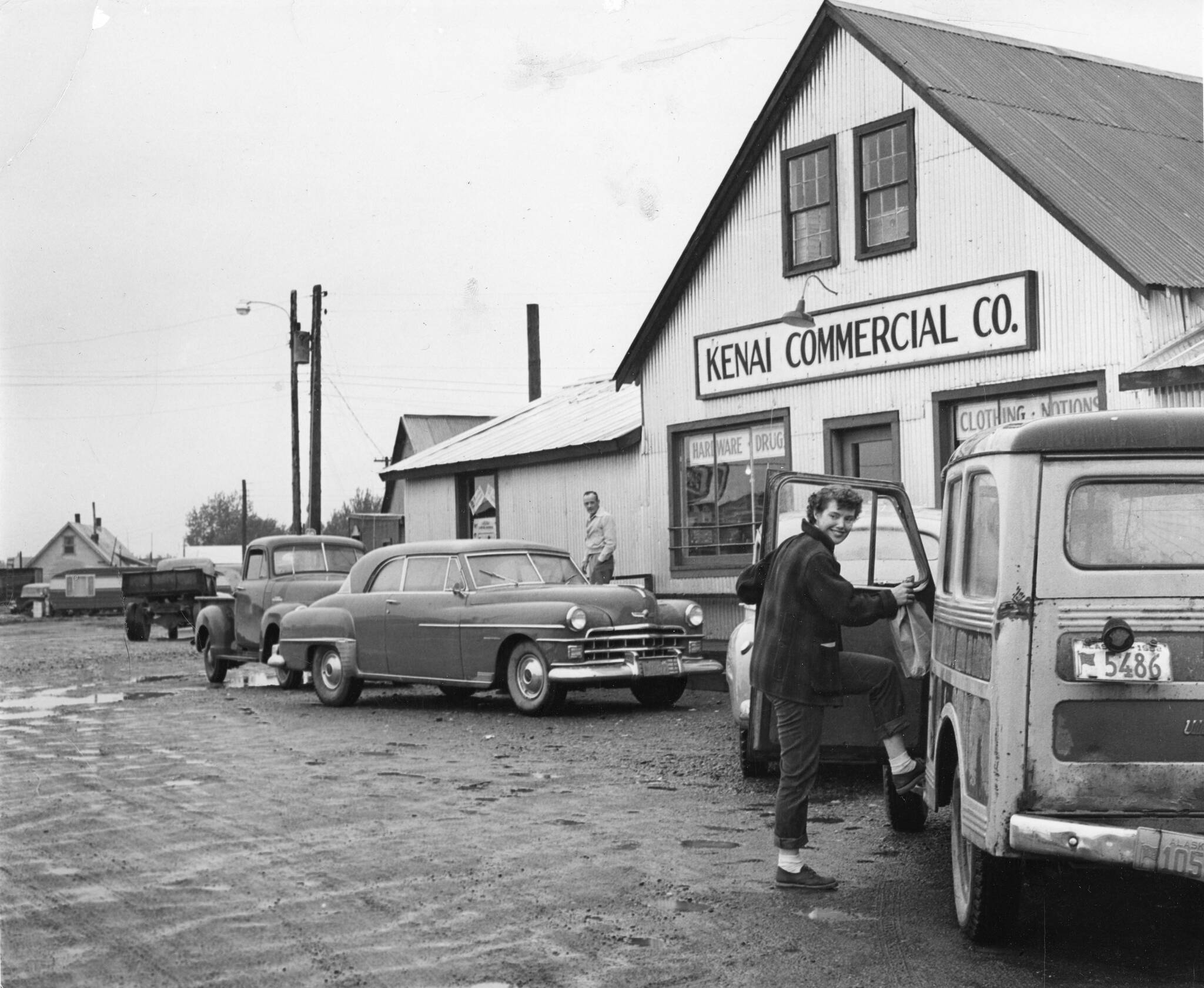 1954 photo by Bob and Ira Spring for Better Homes & Garden magazine
[1a—] After doing business in the Kenai Commercial Company store, Rusty Lancashire climbs into family station wagon, with its sagging back bumper, to head for home.