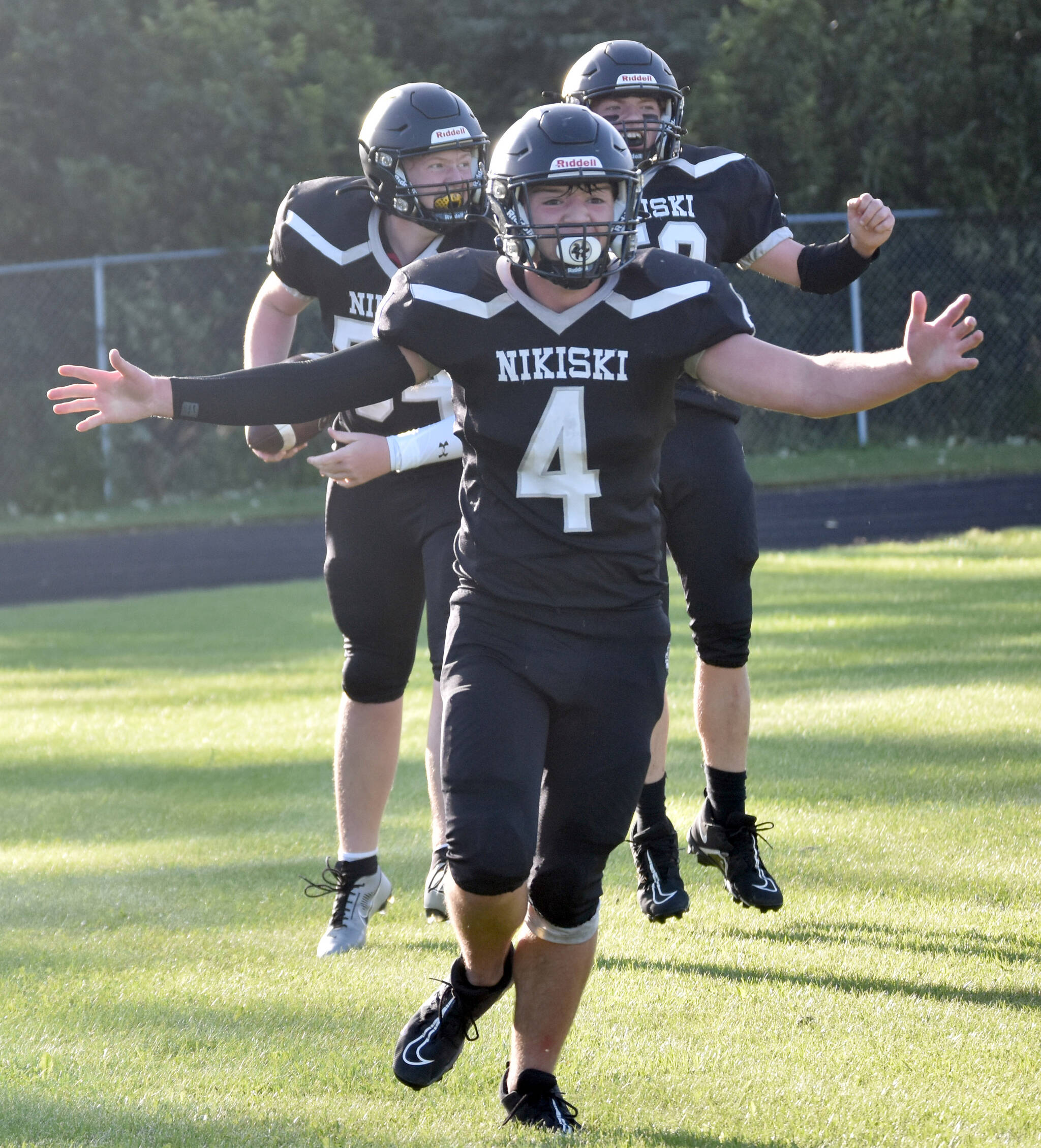 The Nikiski Bulldogs celebrate a touchdown catch by Lynn Deveer against Valdez on Friday, Sept. 1, 2023, at Nikiski Middle-High School in Nikiski, Alaska. Oliver Parrish is in front, while Deveer and Jerry Snodgrass are in the back. (Photo by Jeff Helminiak/Peninsula Clarion)