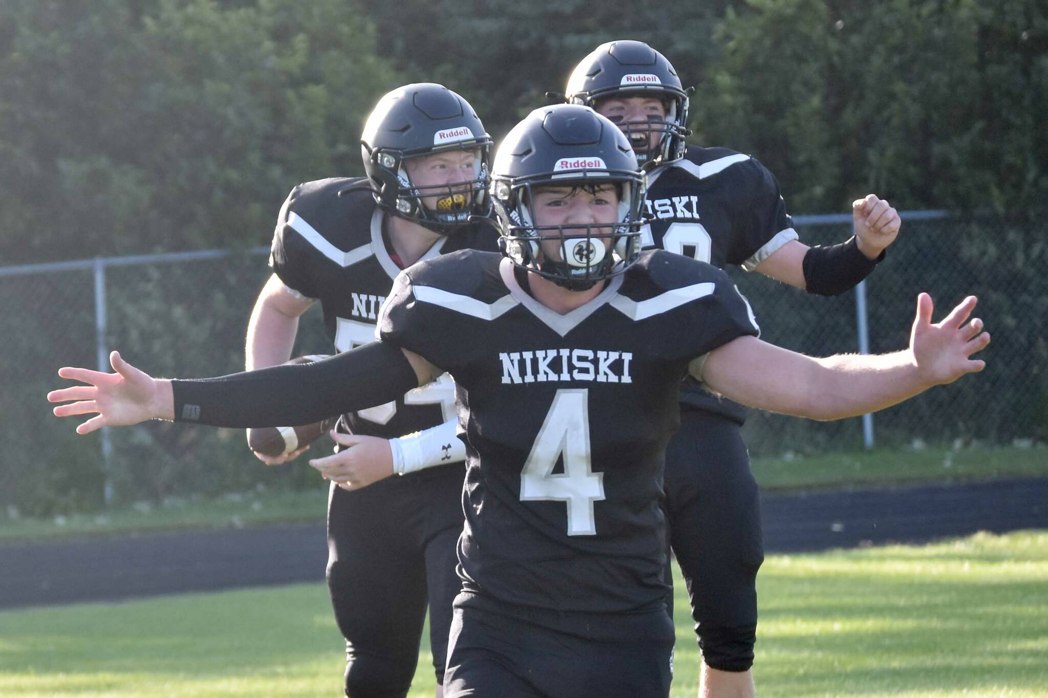 The Nikiski Bulldogs celebrate a touchdown catch by Lynn Deveer against Valdez on Friday, Sept. 1, 2023, at Nikiski Middle-High School in Nikiski, Alaska. Oliver Parrish is in front, while Deveer and Jerry Snodgrass are in the back. (Photo by Jeff Helminiak/Peninsula Clarion)