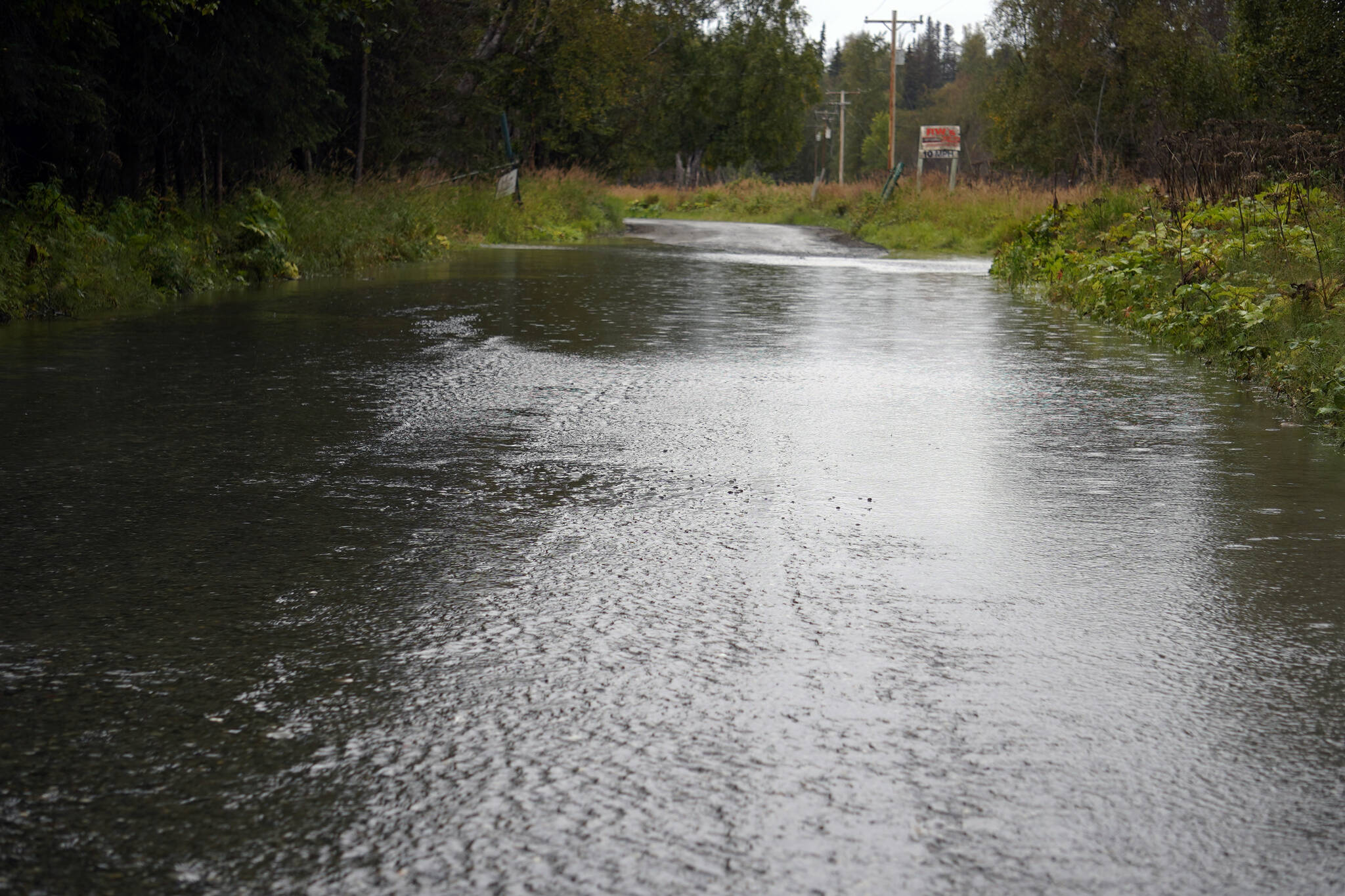 Water runs over Big Eddy Road in Soldotna, Alaska, on Tuesday, Sept. 12, 2023. (Jake Dye/Peninsula Clarion)