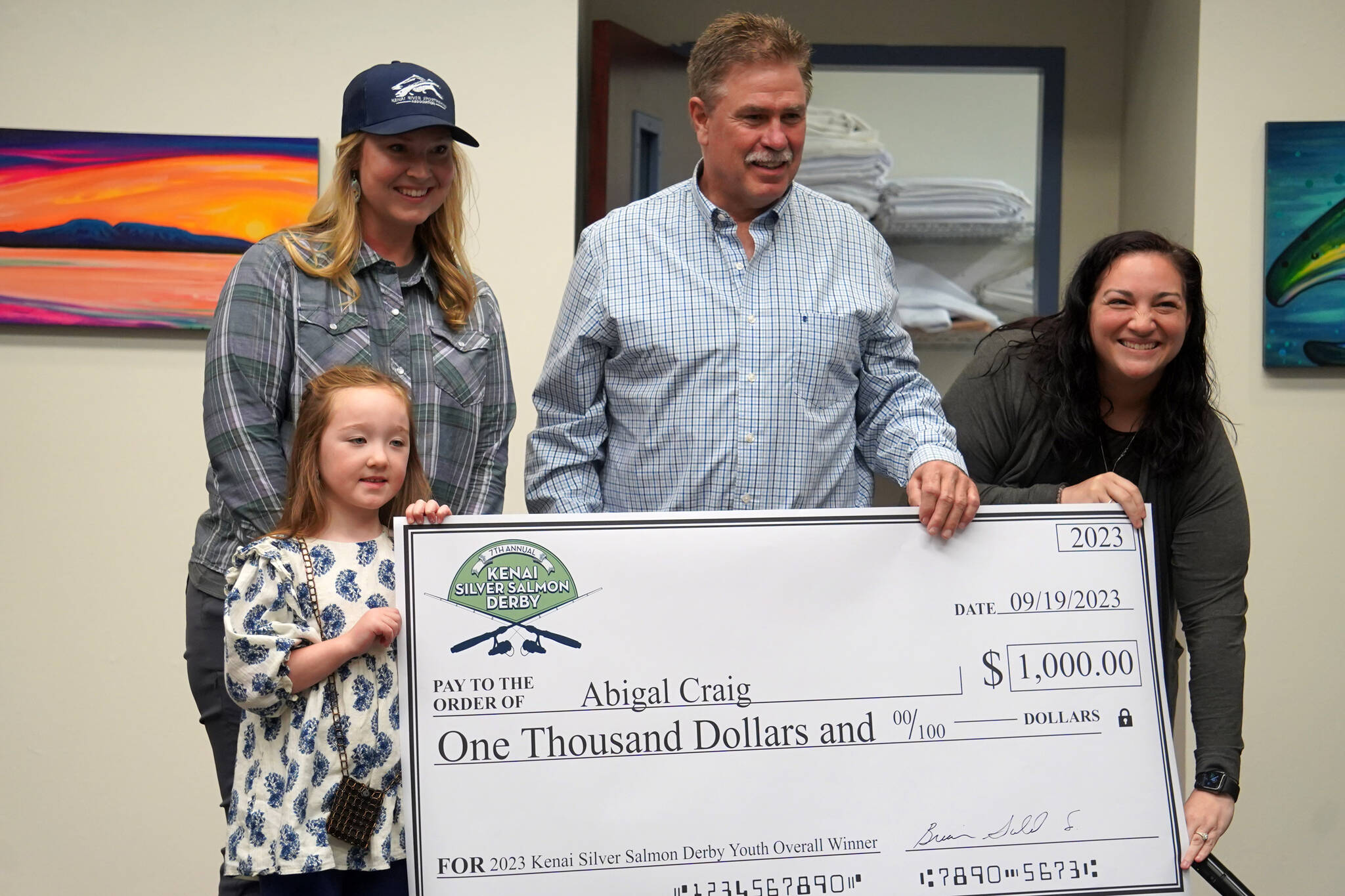 Abigal Craig, youth winner of the Seventh Annual Kenai Silver Salmon Derby, is presented a novelty check by Kenai River Sportfishing Association Executive Director Shannon Martin, City of Kenai Mayor Brian Gabriel, and Kenai Chamber of Commerce Executive Director Samantha Springer at the Kenai Chamber of Commerce and Visitor Center in Kenai, Alaska, on Wednesday, Sept. 20, 2023. (Jake Dye/Peninsula Clarion)