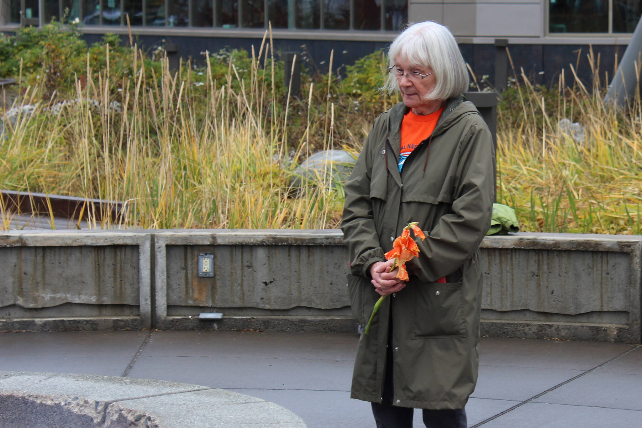 Mary Hunt, a survivor of Holy Cross Mission, holds flowers during an Orange Shirt Day ceremony at Ggugguyni T'uh, "Raven Place," outside the Dena'ina Wellness Center on Friday, Oct. 6, 2023 in Kenai, Alaska. Orange Shirt Day honors indigenous elders who survived and children lost from boarding schools established to detribalize indigenous people. (Ashlyn O'Hara/Peninsula Clarion)