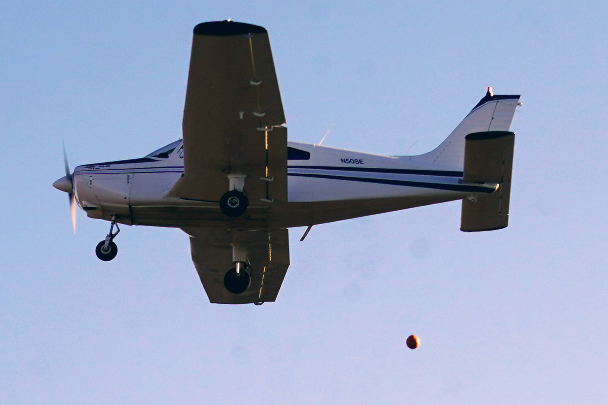 A pumpkin is released from a plane during Kenai Aviation’s Fifth Annual Pumpkin Drop at the Kenai Airpark in Kenai, Alaska, on Saturday, Oct. 21, 2023. (Jake Dye/Peninsula Clarion)