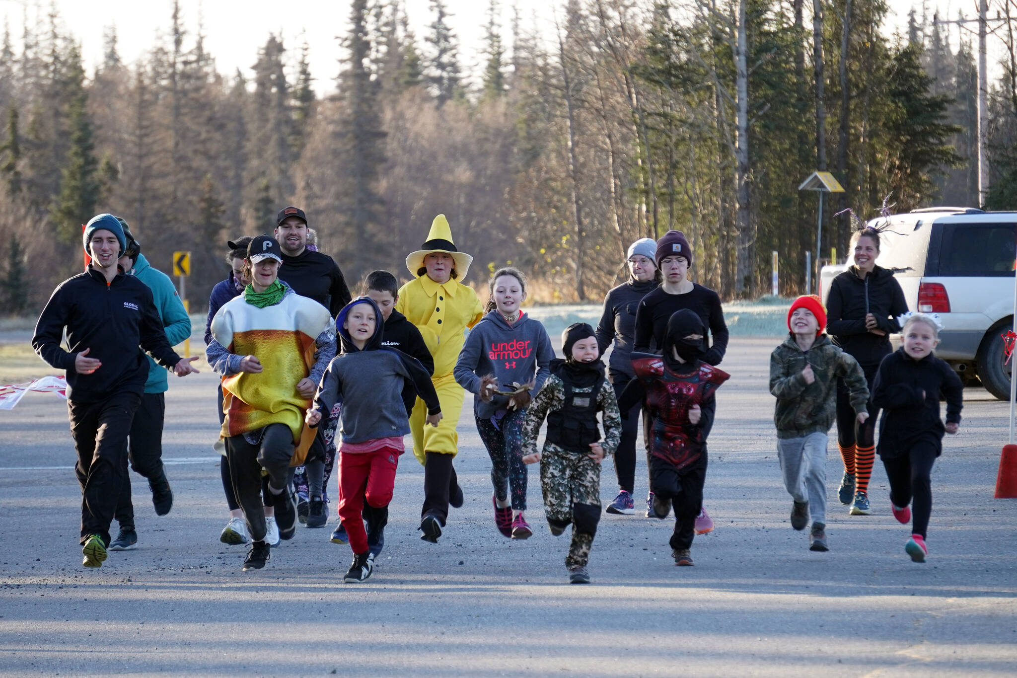 A pack of runners, in costumes and in warm clothes, take off at the start of the Costume Caper at Nikiski Community Recreation Center in Nikiski, Alaska, on Saturday, Oct. 21, 2023. (Jake Dye/Peninsula Clarion)