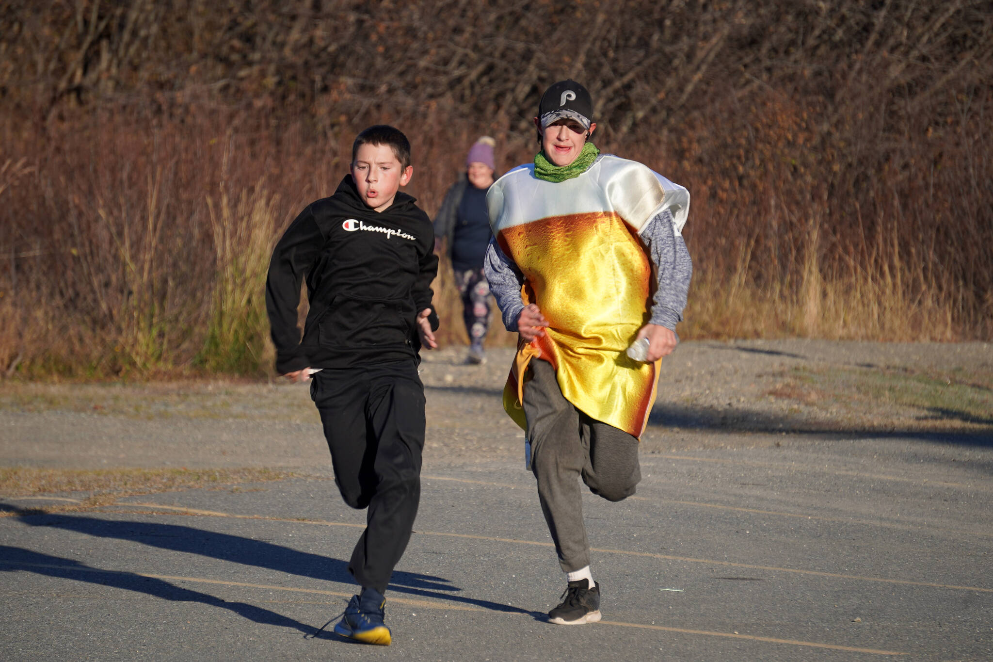 Wyatt Kingery and Dominic Smith race side by side to the finish chute of the Costume Caper at Nikiski Community Recreation Center in Nikiski, Alaska, on Saturday, Oct. 21, 2023. (Jake Dye/Peninsula Clarion)