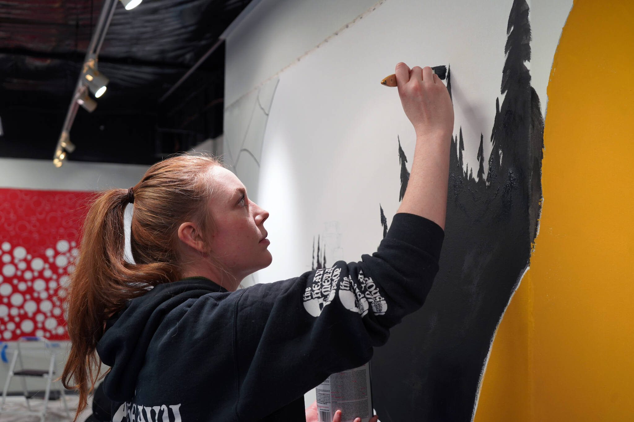 Morgan Chamberlain works on a section of the mural at the Kenai Art Center in Kenai, Alaska, on Wednesday, Nov. 1, 2023. (Jake Dye/Peninsula Clarion)