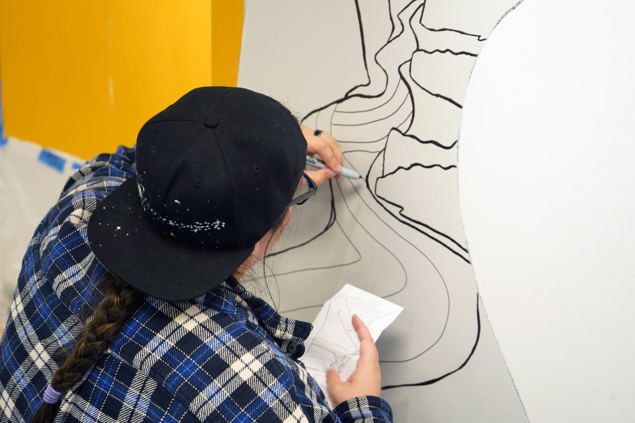 Rachael Montoya works on a section of the mural at the Kenai Art Center in Kenai, Alaska, on Wednesday, Nov. 1, 2023. (Jake Dye/Peninsula Clarion)
