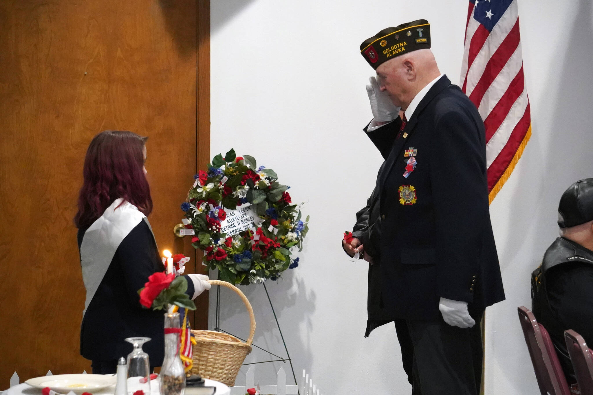 Attendees of a Veterans Day ceremony and potluck place poppies on a symbolic grave at the American Legion Post 20 in Kenai, Alaska, on Saturday, Nov. 11, 2023. (Jake Dye/Peninsula Clarion)