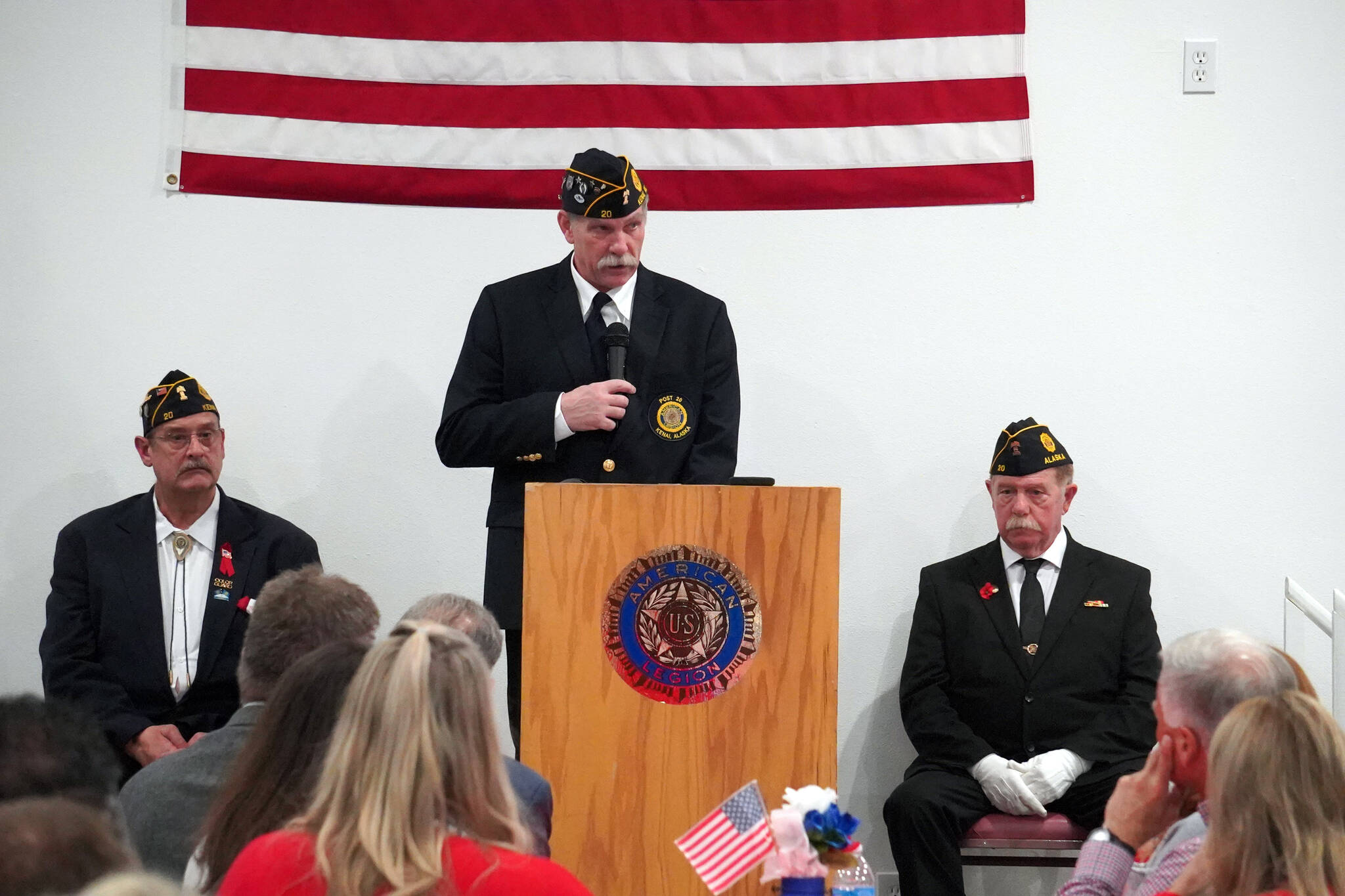 American Legion Post 20 Cmdr. Ron Homan, center, is joined onstage by Past Cmdr. Dave Segura and Chaplain Mike Meredith while speaking during a Veterans Day celebration at the American Legion Post 20 in Kenai, Alaska, on Saturday, Nov. 11, 2023. (Jake Dye/Peninsula Clarion)