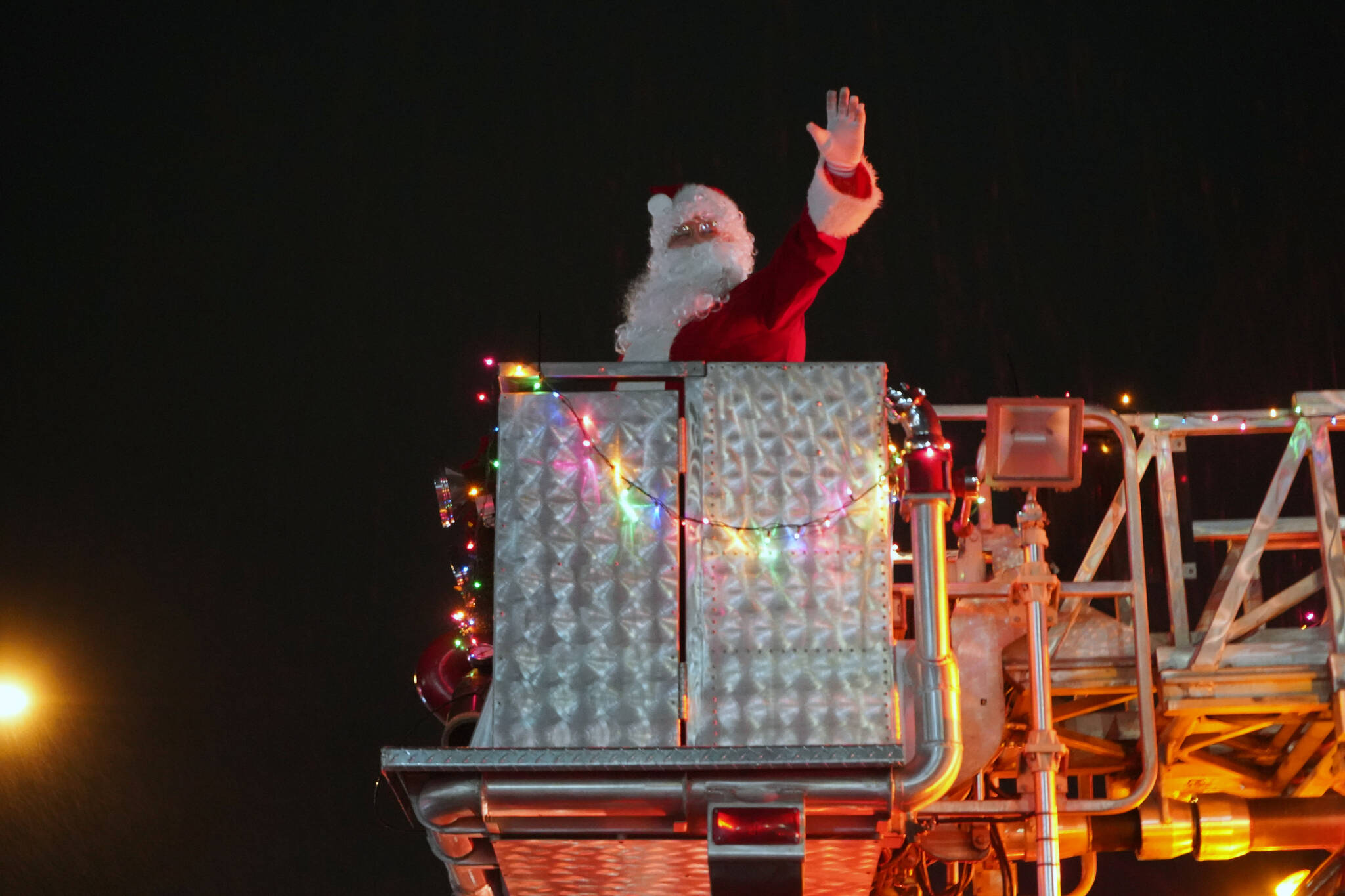 Santa Claus greets children during the Electric Lights Parade, part of Christmas Comes to Kenai festivities, along Frontage Road in Kenai, Alaska, on Friday, Nov. 24, 2023. (Jake Dye/Peninsula Clarion)