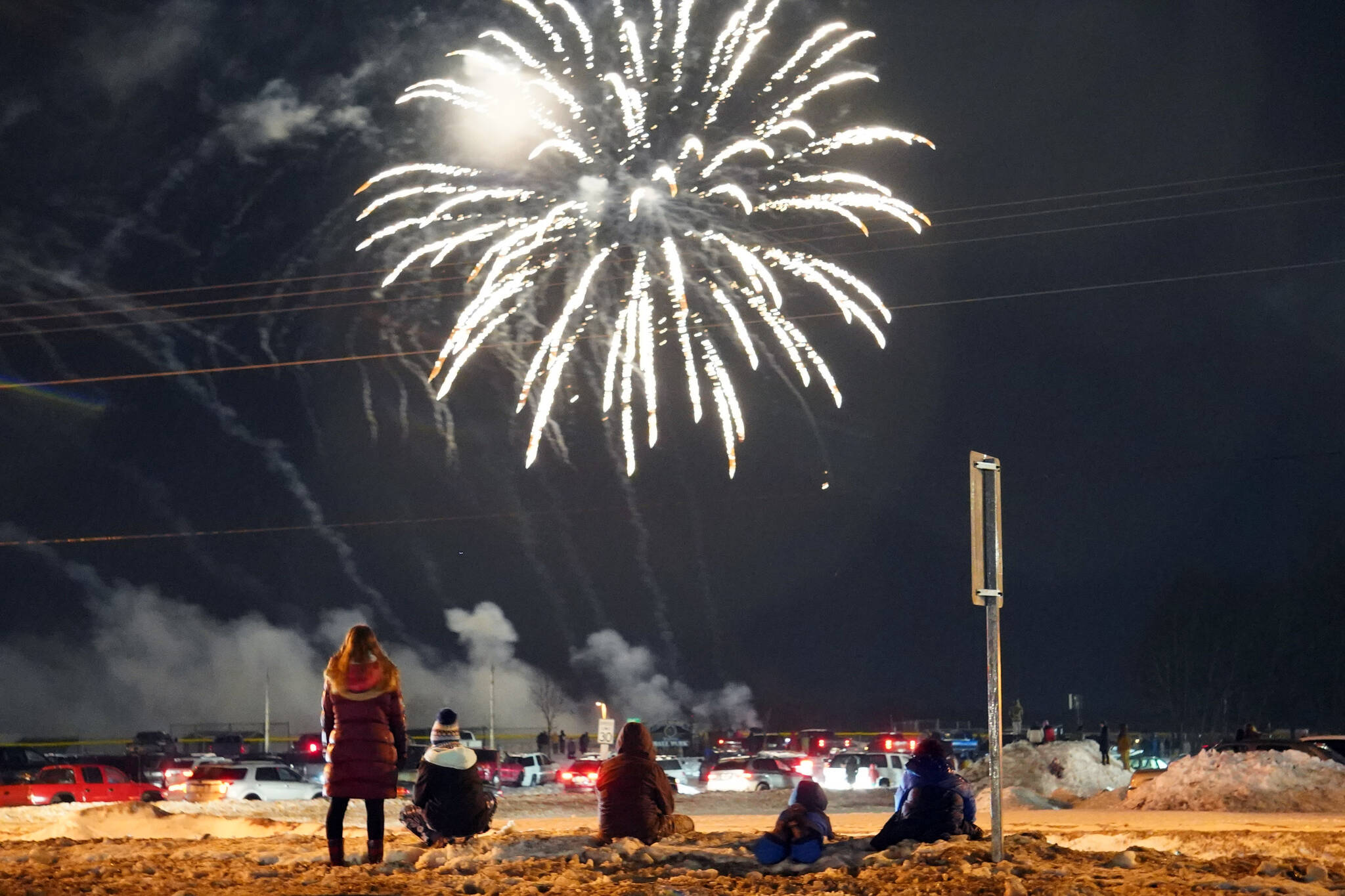 Kids watch fireworks under rainfall during Christmas Comes to Kenai festivities along Frontage Road in Kenai, Alaska, on Friday, Nov. 24, 2023. (Jake Dye/Peninsula Clarion)
