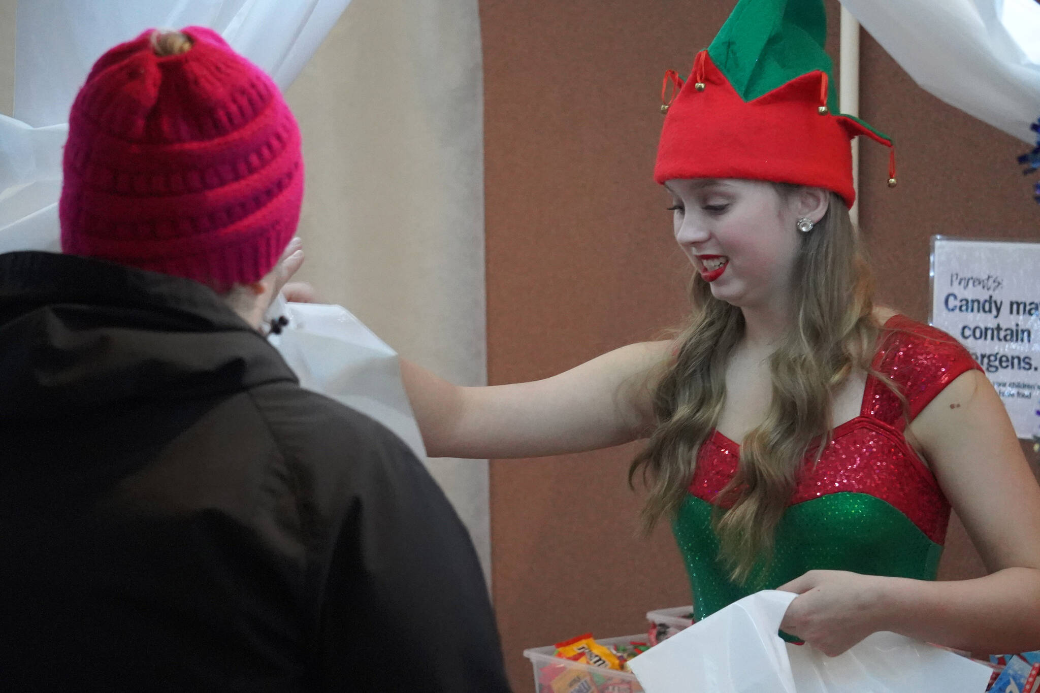 One of the Forever Dance elves passes out bags of candy and gifts during Christmas Comes to Kenai festivities at the Kenai Chamber of Commerce and Visitor Center in Kenai, Alaska, on Friday, Nov. 24, 2023. (Jake Dye/Peninsula Clarion)