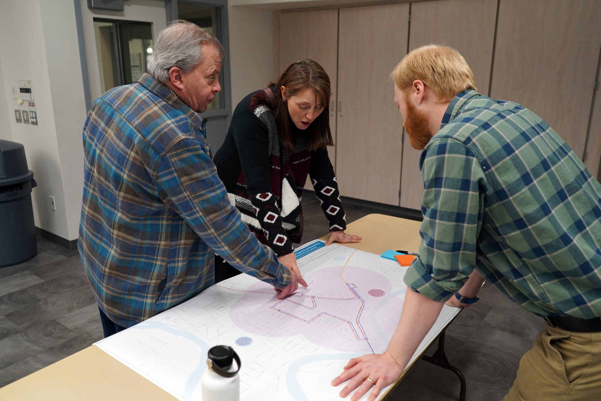 Tim Navarre and Dana Cannava discuss a preliminary Soldotna route for the Kahtnu Area Transit with Planner Bryant Wright at the Challenger Learning Center of Alaska in Kenai, Alaska, on Wednesday, Nov. 29, 2023. (Jake Dye/Peninsula Clarion)